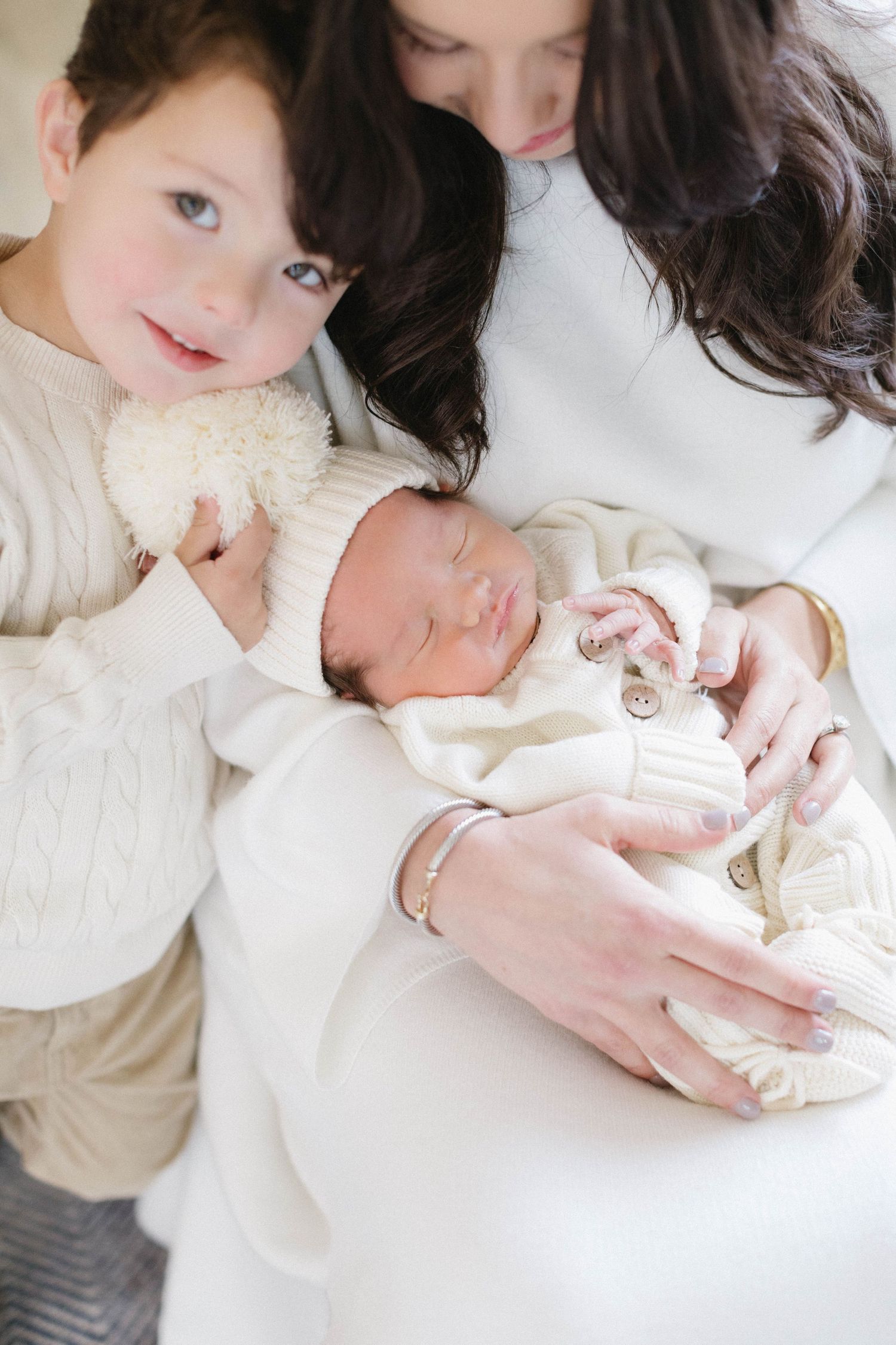 A tender family moment as a newborn baby rests peacefully on soft white blankets.