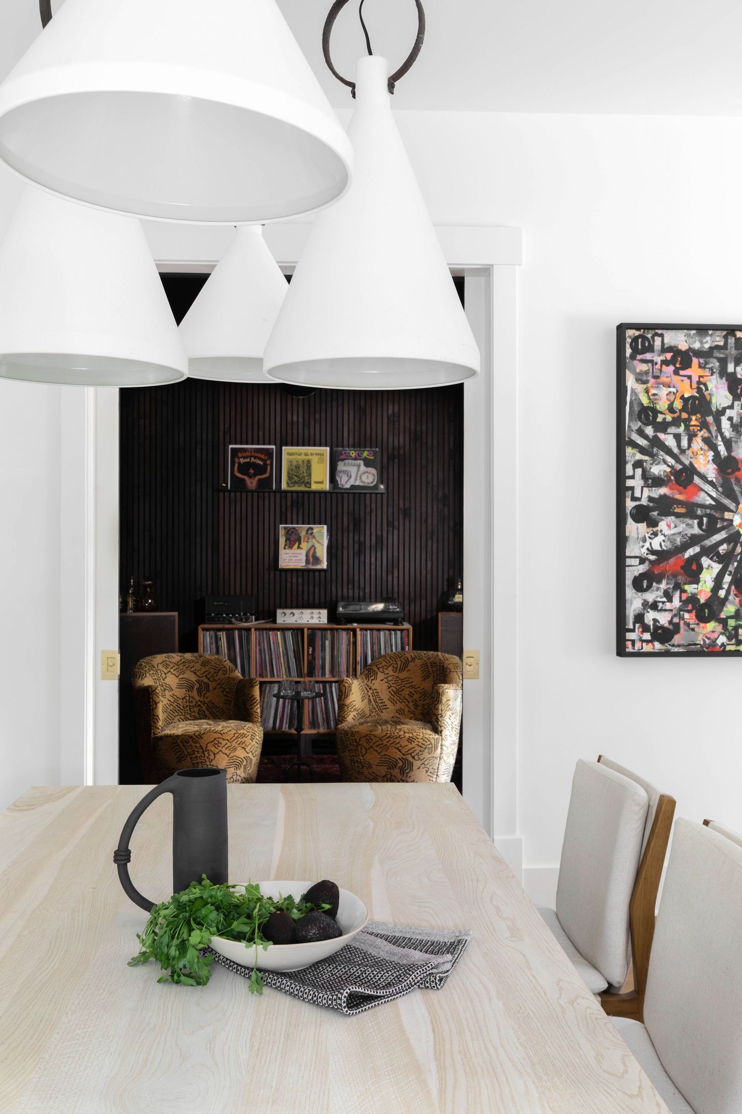 Modern dining room with white pendant lights and brown accent chairs against black wood paneling. Atlanta Interior Design Photography