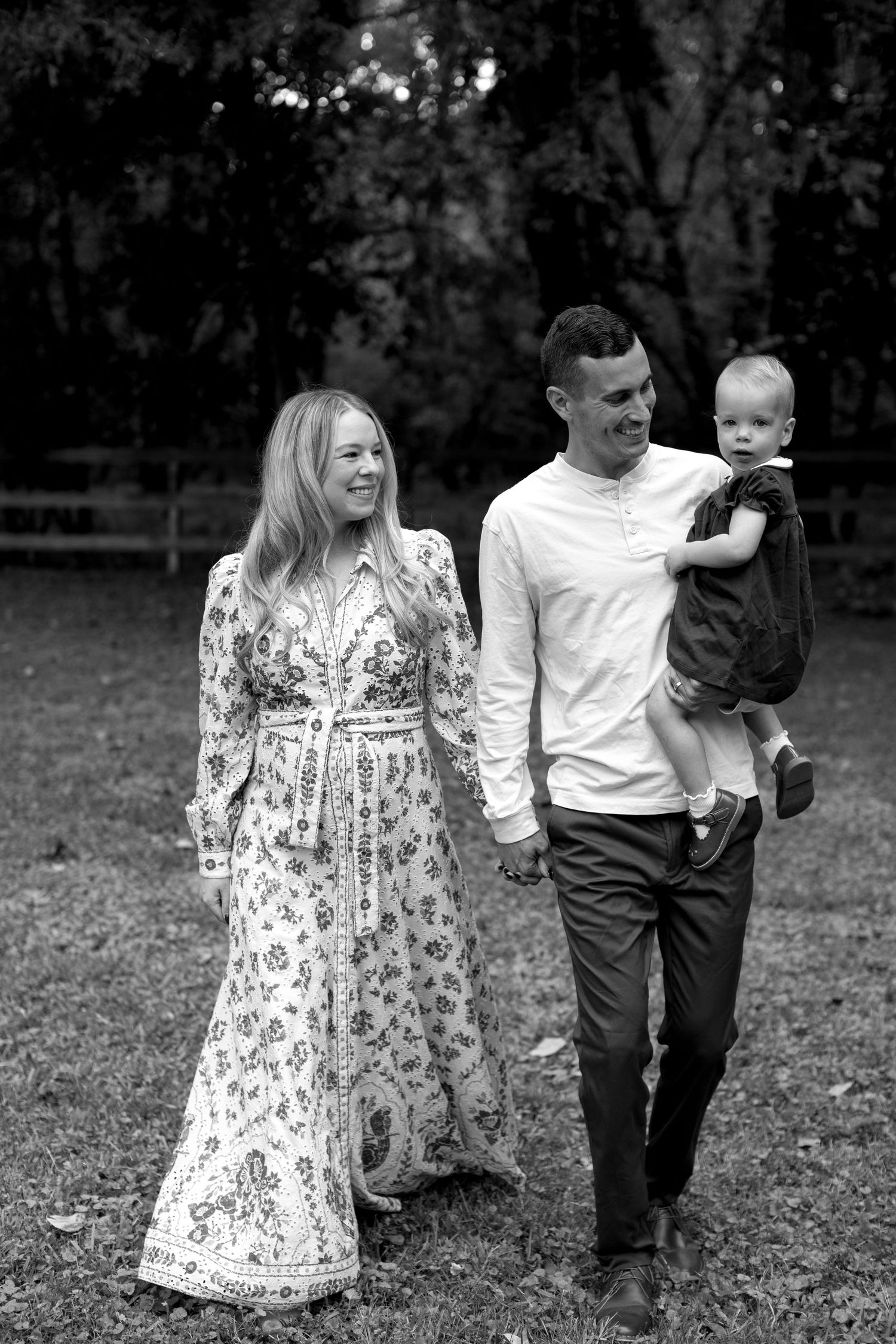 A family walks together through a park, with a floral dress and casual attire creating a candid outdoor moment.