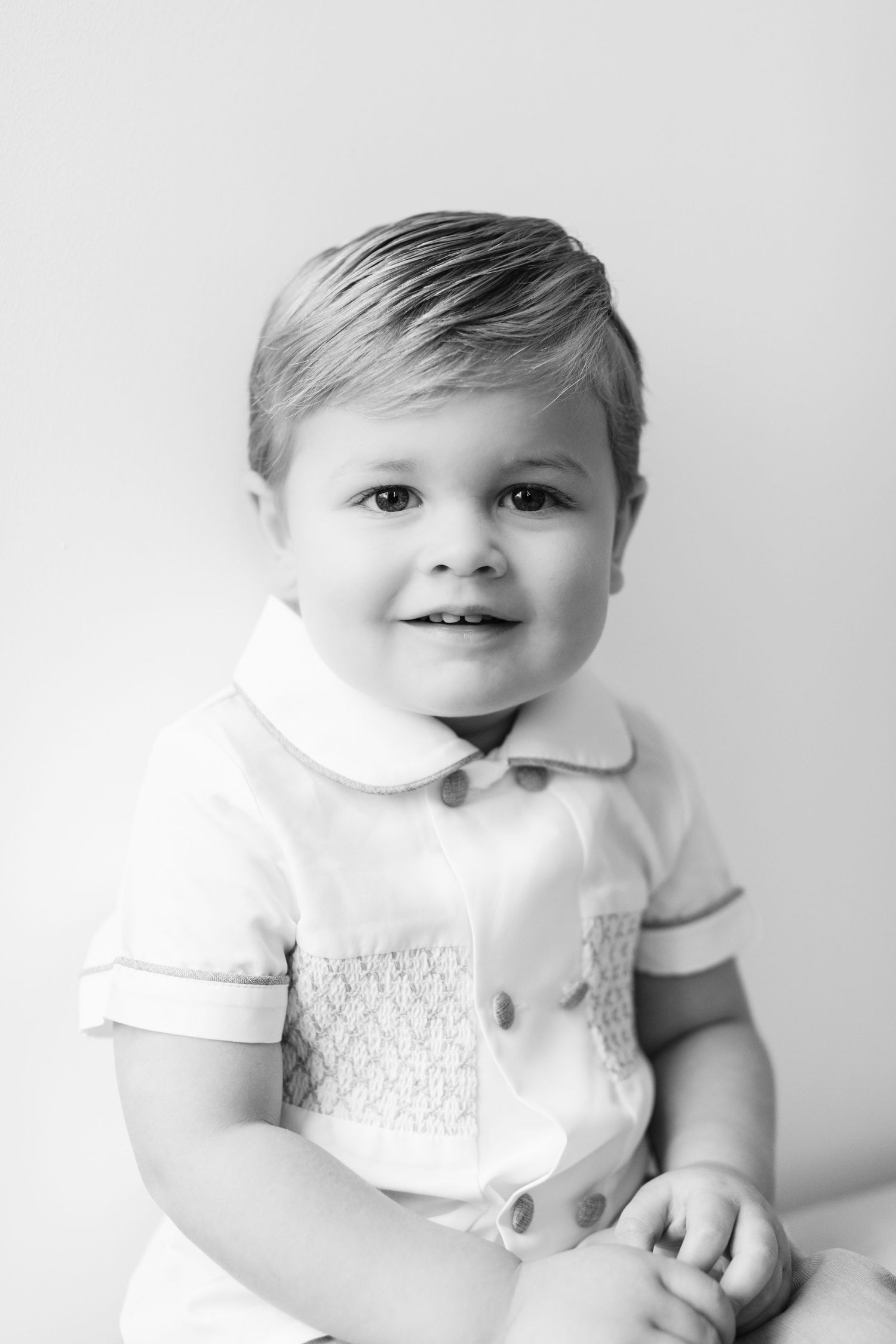 Black and white portrait series of a baby in white clothing against a light background.
