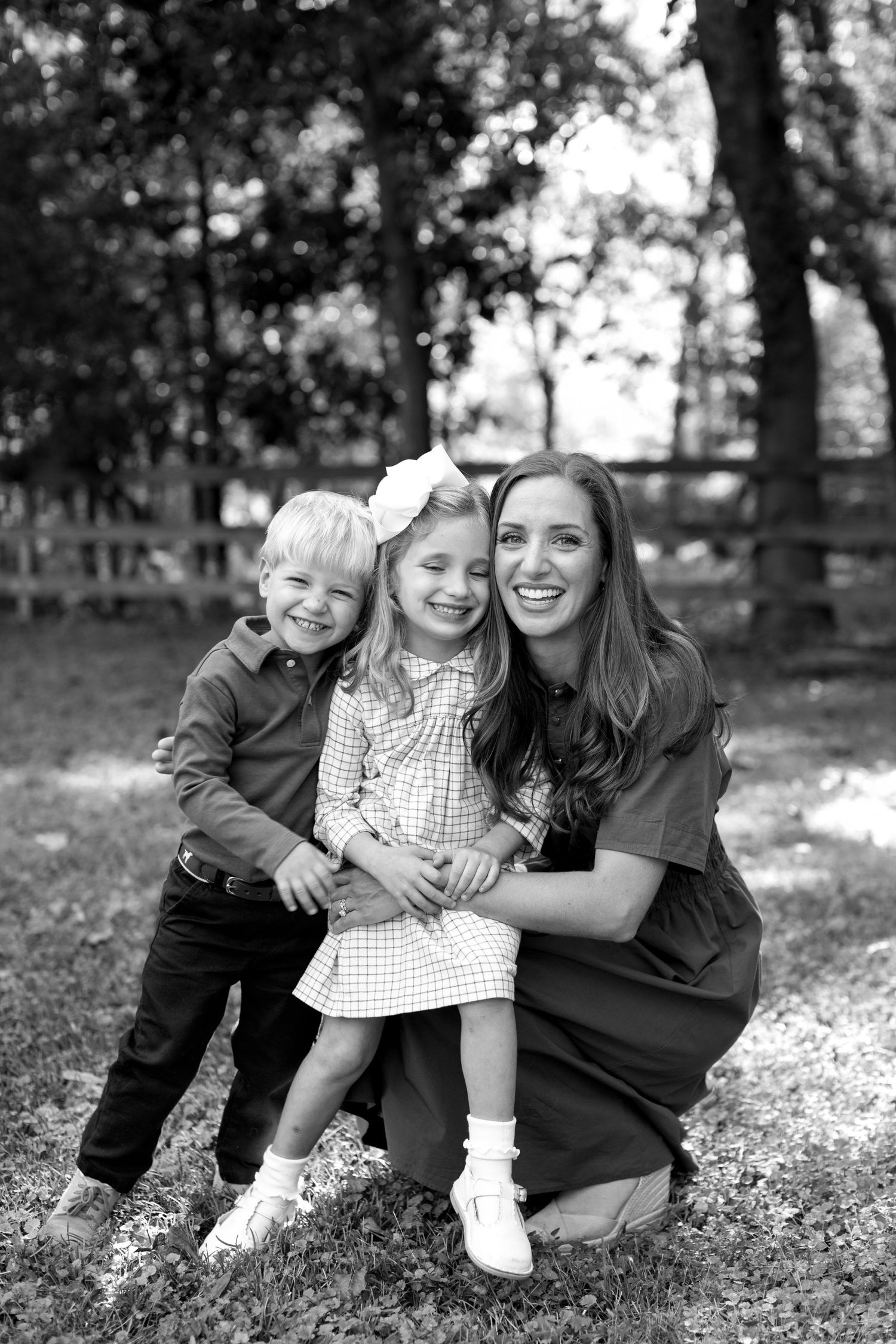 A candid black and white photo sequence shows a playful moment between three people sitting on grass outdoors.