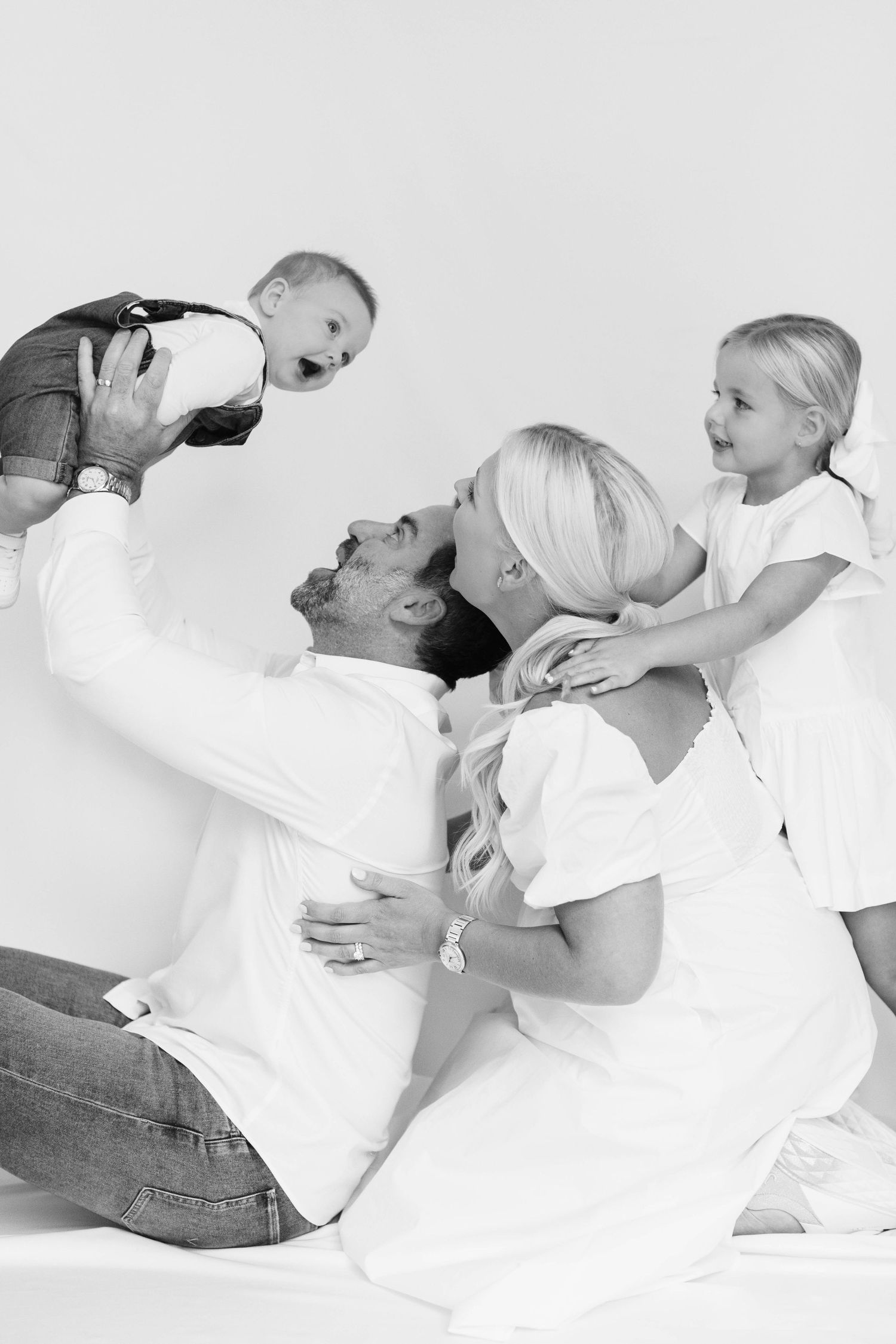 Black and white candid sequence of parent and baby playing and bonding together on white background.