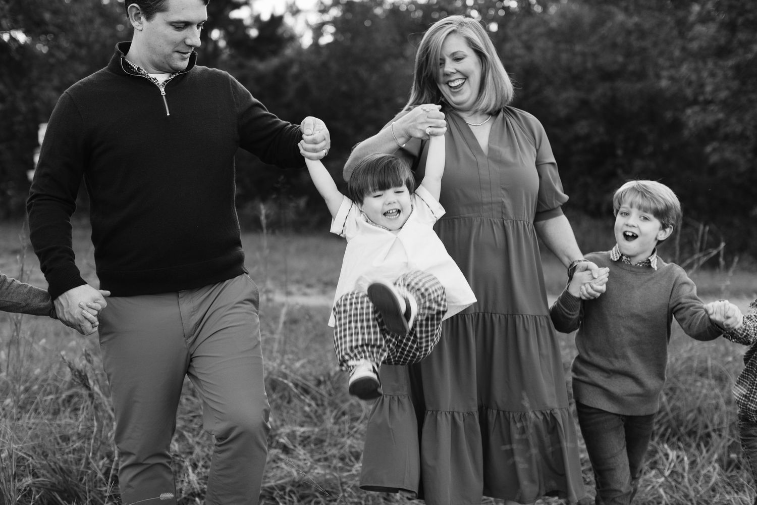 A black and white candid family photo showing playful interaction outdoors.