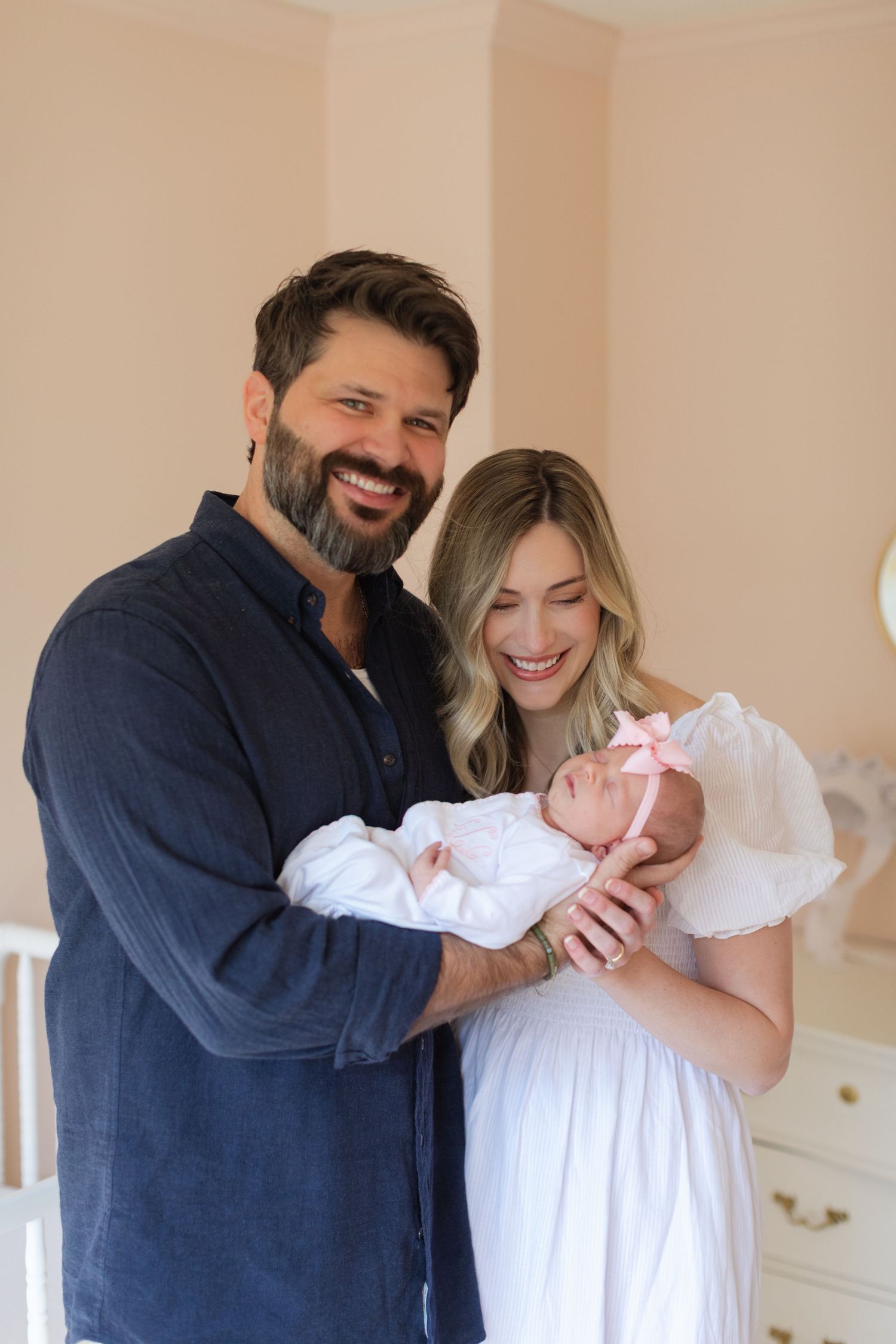 A joyful family moment with new parents holding their newborn baby in a nursery setting.