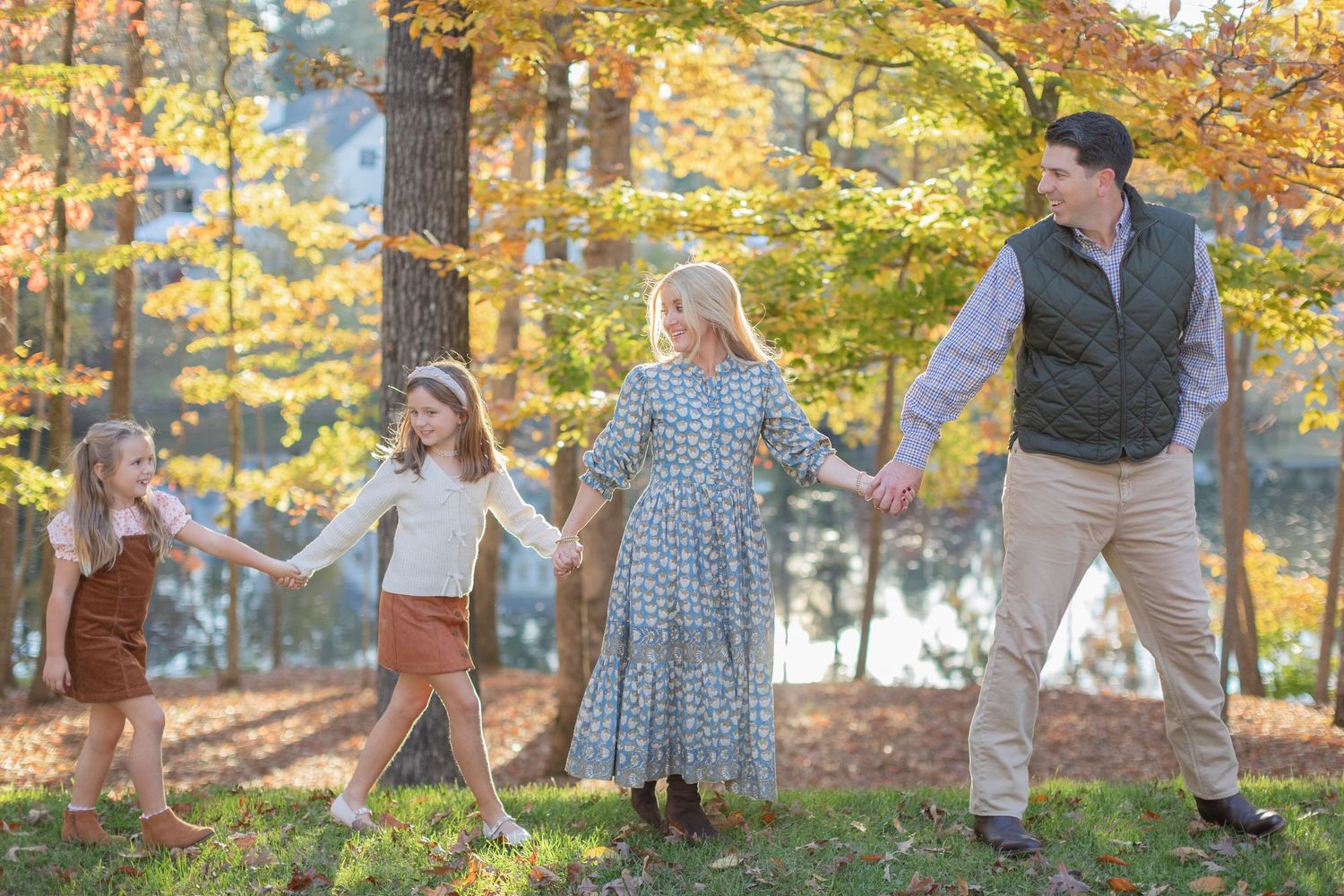 Family enjoying a playful autumn day together in a park with golden fall foliage in the background.
