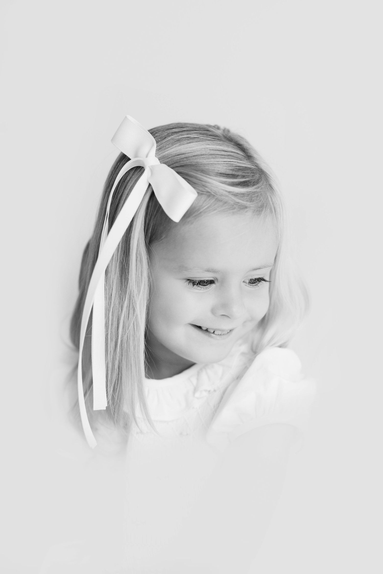 Black and white portraits showing expressions of laughter and joy with white bows in hair.
