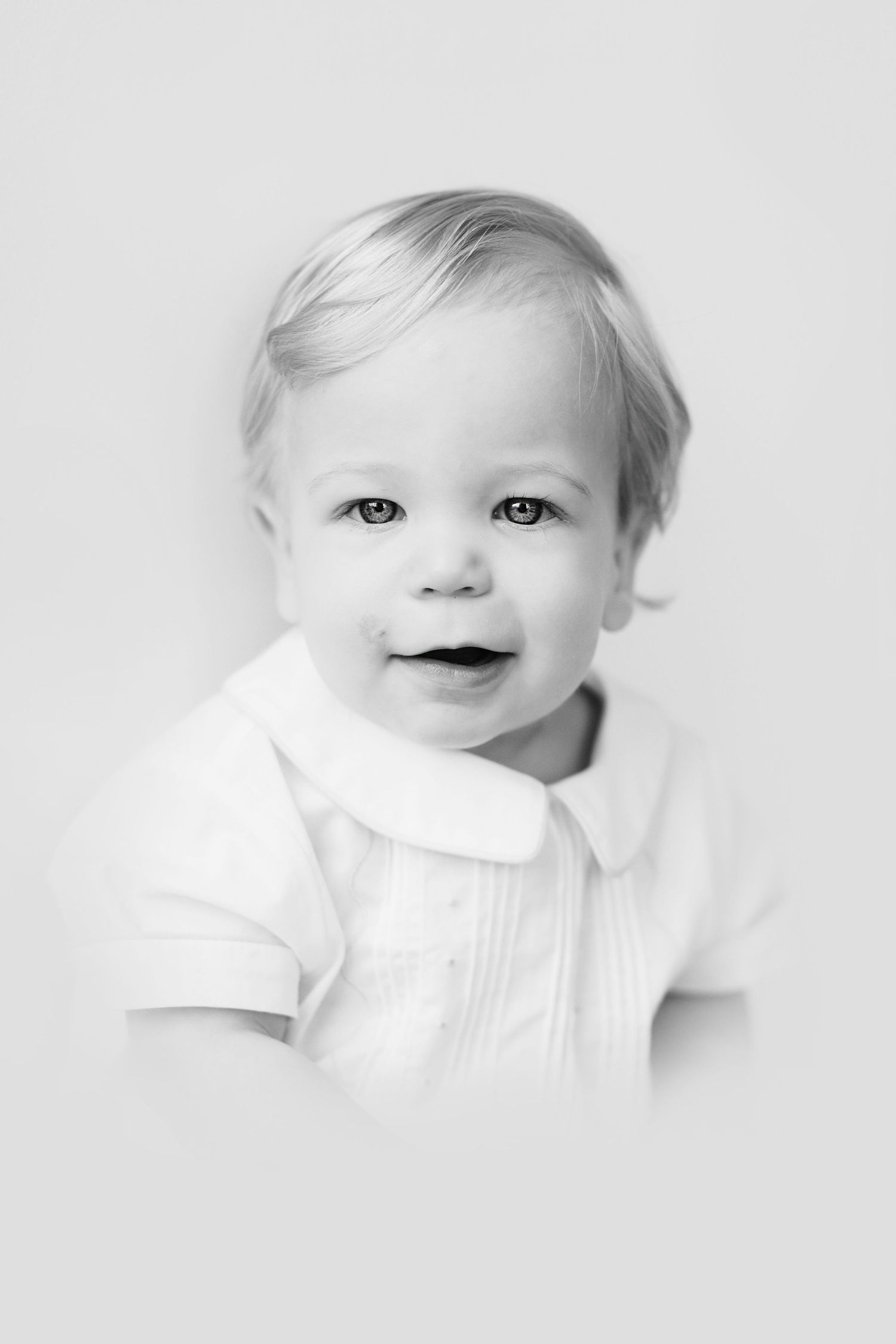 High key black and white portrait series showing a baby with light hair making playful expressions.