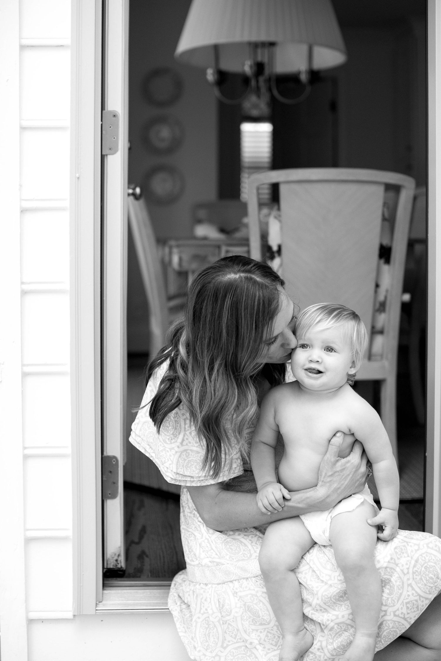 A touching black and white collage shows tender moments between a parent and baby on a white bedspread.