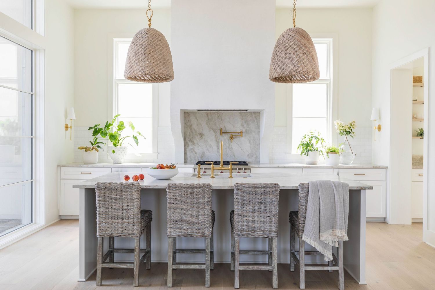 A modern white kitchen with woven barstools, pendant lights, and marble backsplash - Atlanta Interior Design Photography