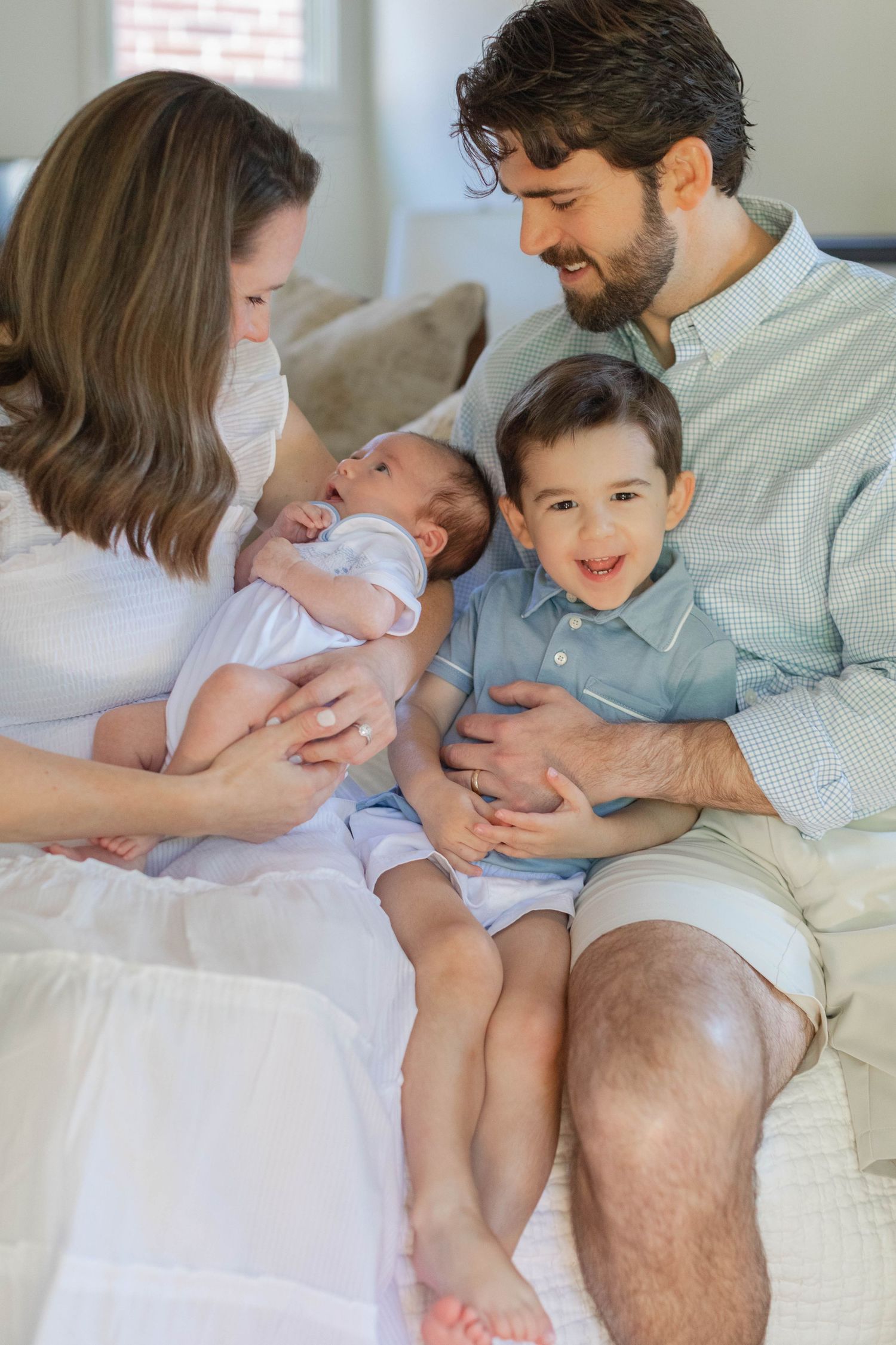 Five heartwarming frames show a family bonding with their newborn baby and toddler sibling on a white couch.