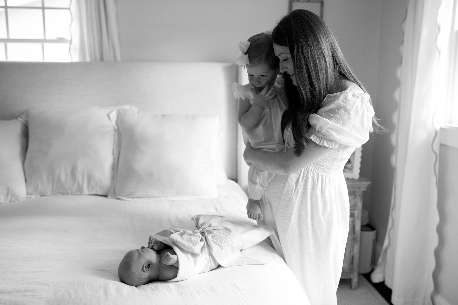A series of black and white photos showing pillow fighting on a bed wearing white nightgowns.
