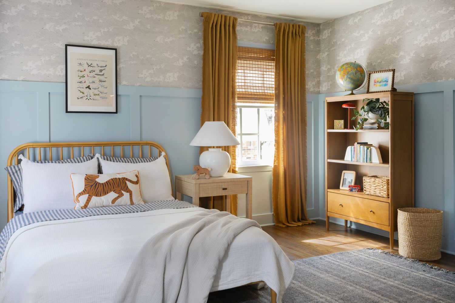 A cozy bedroom features light blue walls, mustard yellow curtains, and natural wood accents with warm lighting.