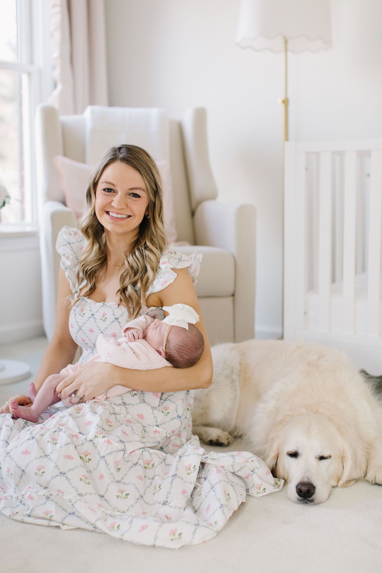 A peaceful nursery scene with a newborn baby and sleeping Great Pyrenees dog on a plush white carpet.