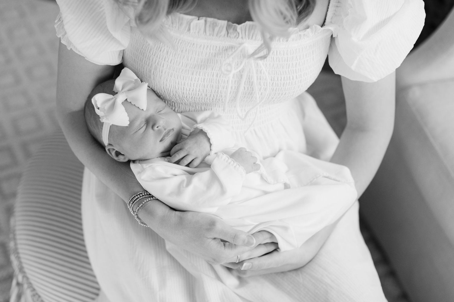 A close-up black and white photo of tiny newborn baby feet being cradled in white fabric.