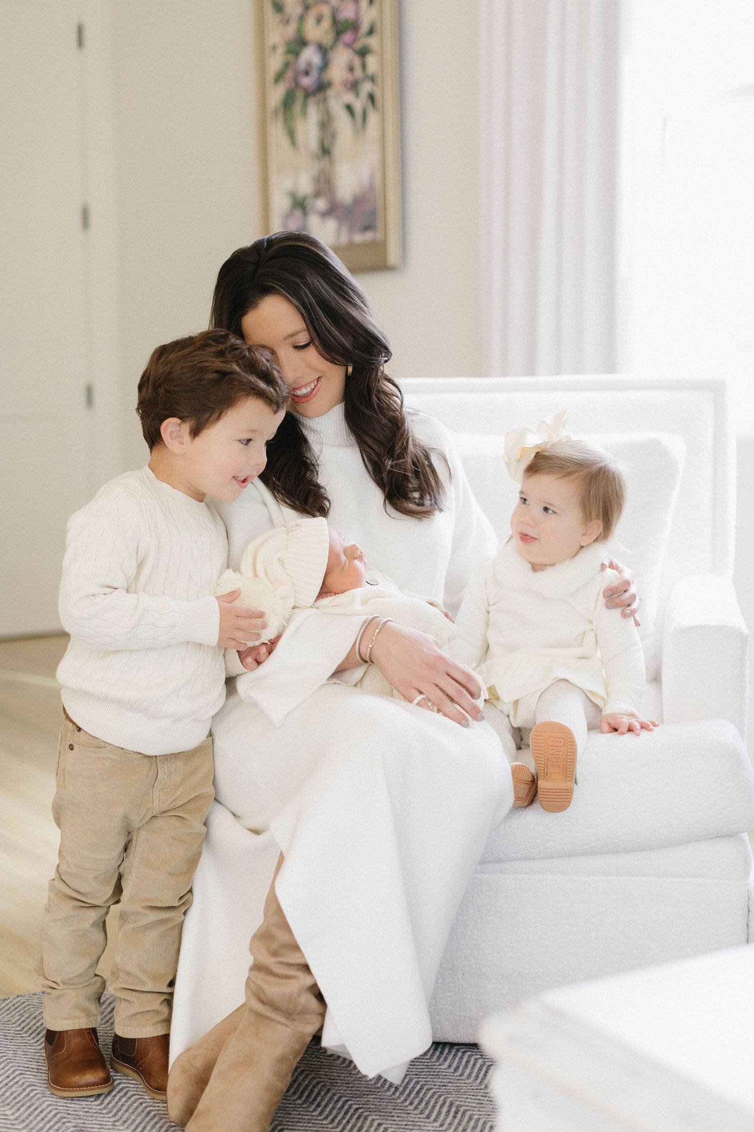 Candid family interaction on white couch showing playful moments in matching outfits.