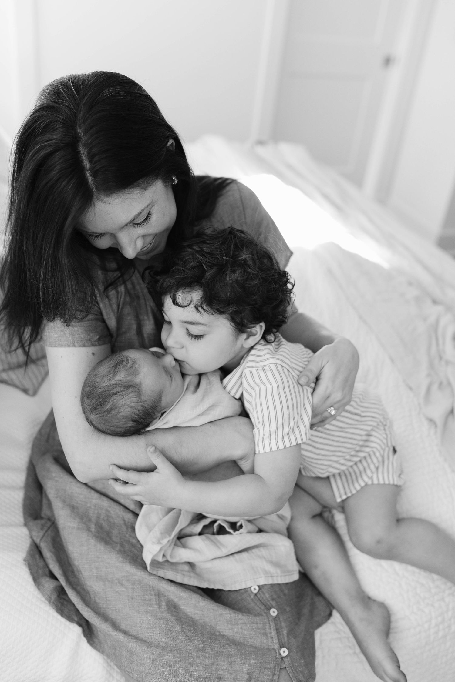 Black and white photo series showing tender moments between mother and baby in bed.