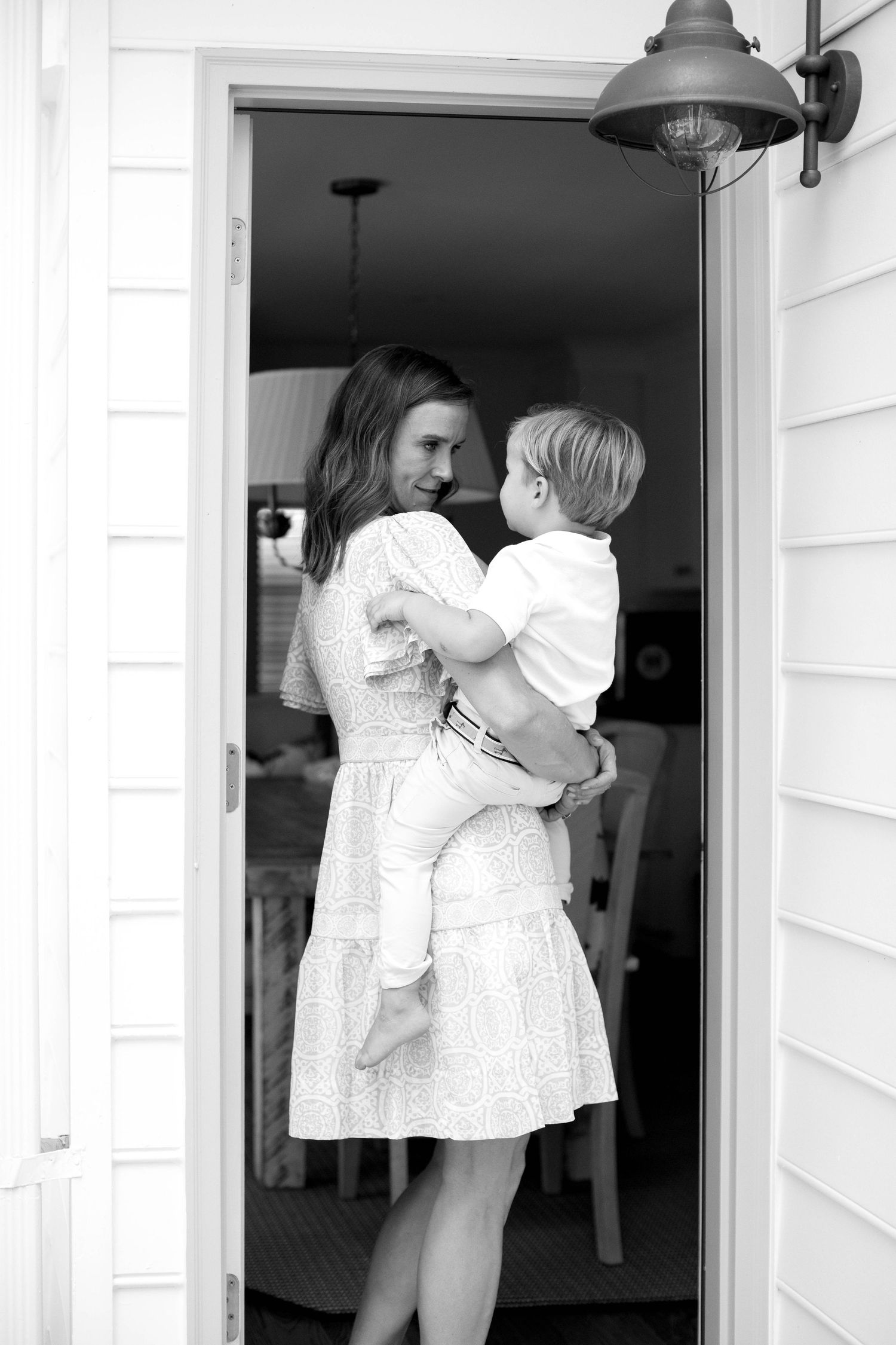 A sweet black and white photo of a tender moment between parent and child in a doorway.