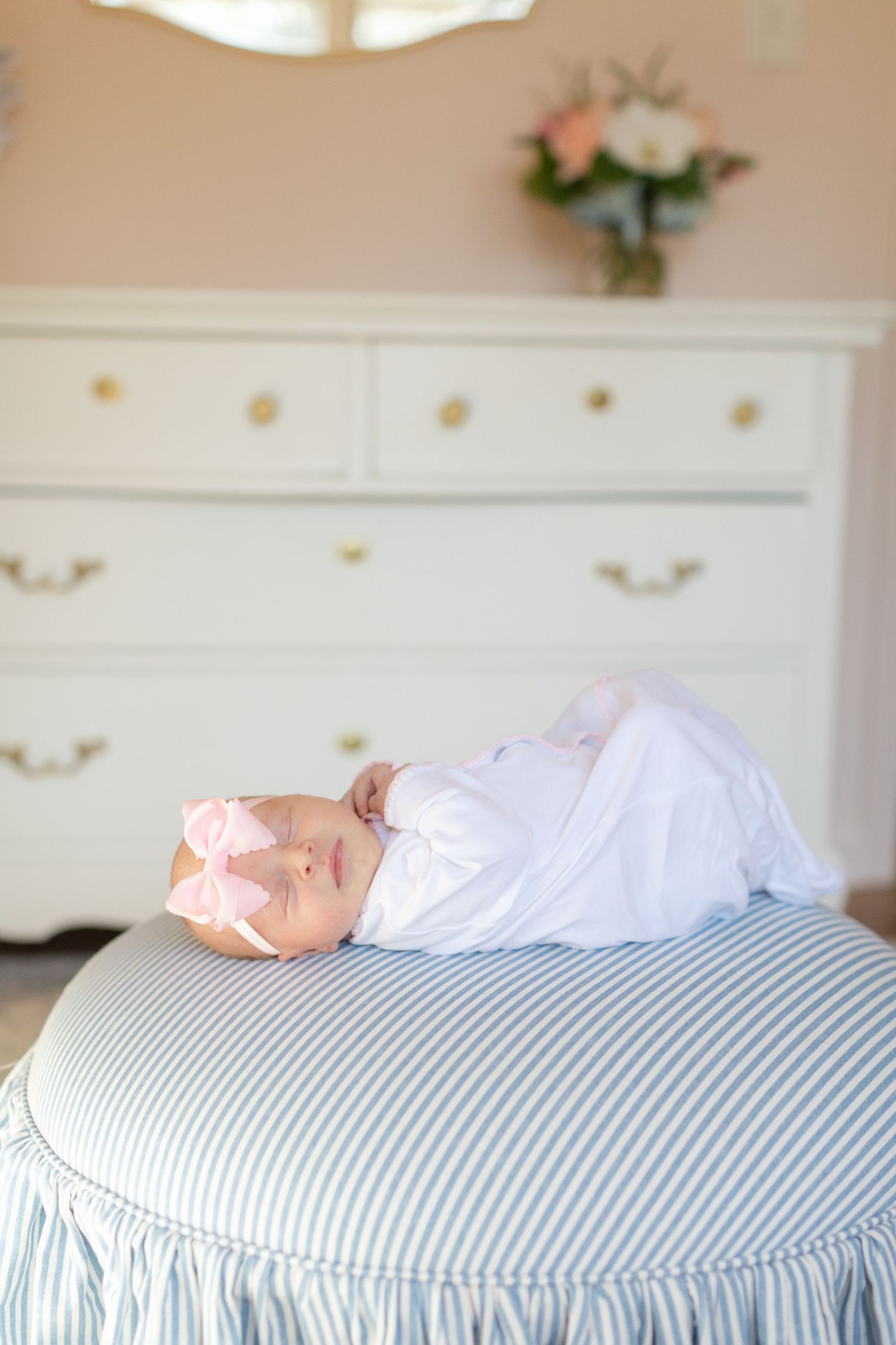 A series of photos showing a sleeping newborn baby on a blue and white striped bed.