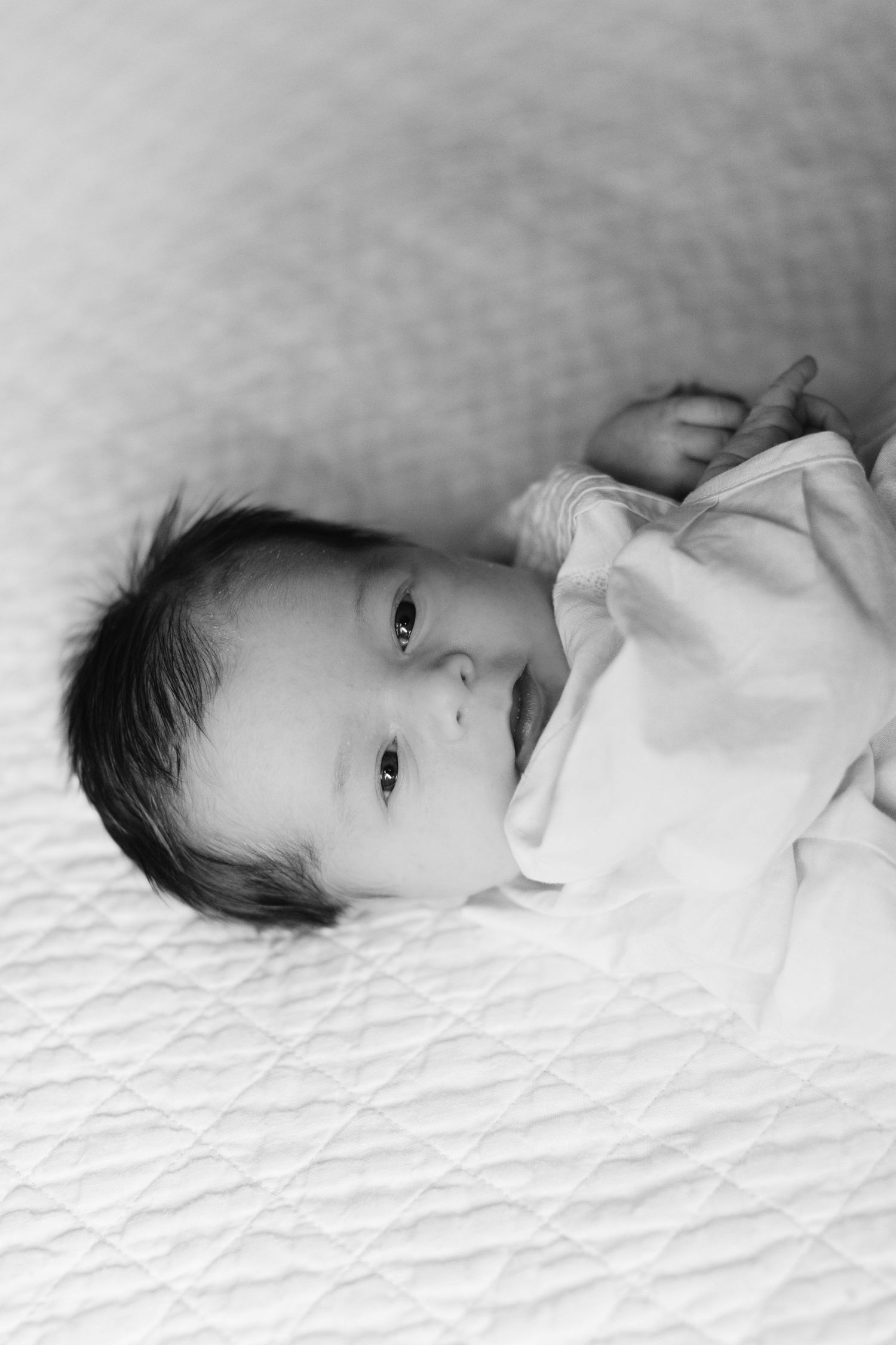 Series of black and white portraits showing newborn baby lying on white textured blanket.