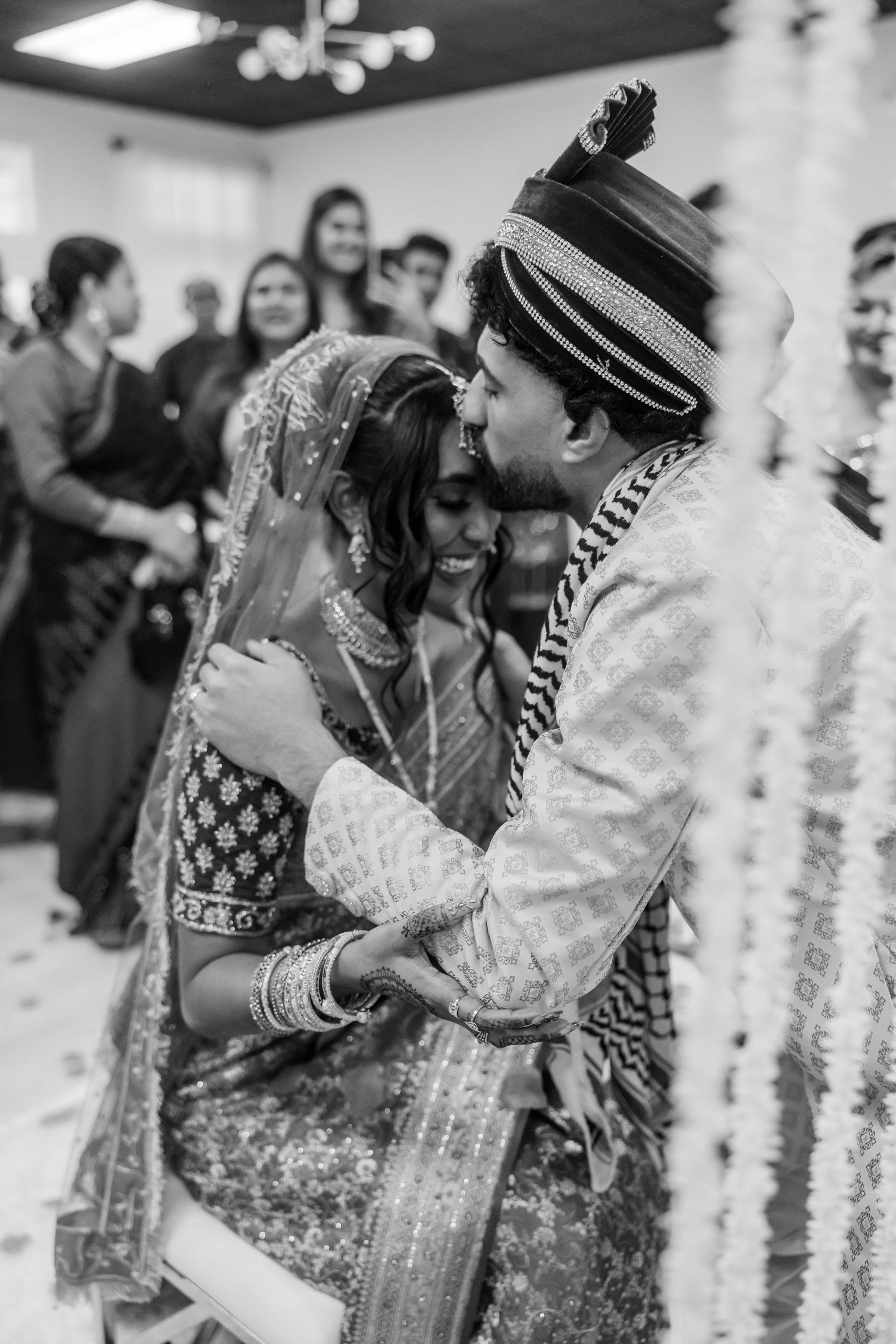 A tender black and white moment between newlyweds during a traditional Indian wedding ceremony.