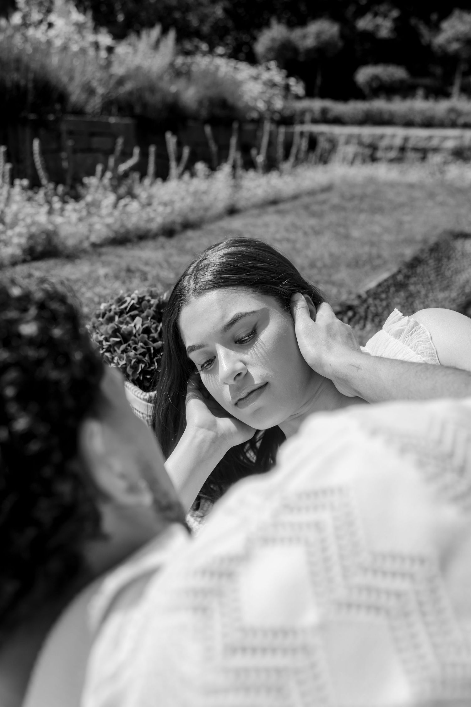 Black and white portraits of a bride resting gracefully in a garden setting.