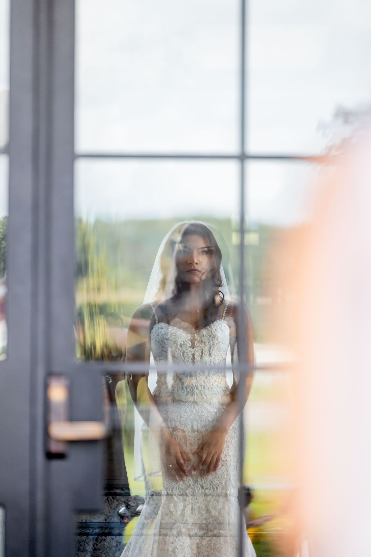 Artistic reflective shots of a bride in a lace wedding dress through window panes.