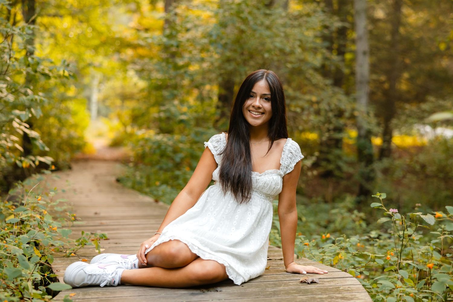 Outdoor portrait session in a park with yellow fall foliage and natural lighting.
