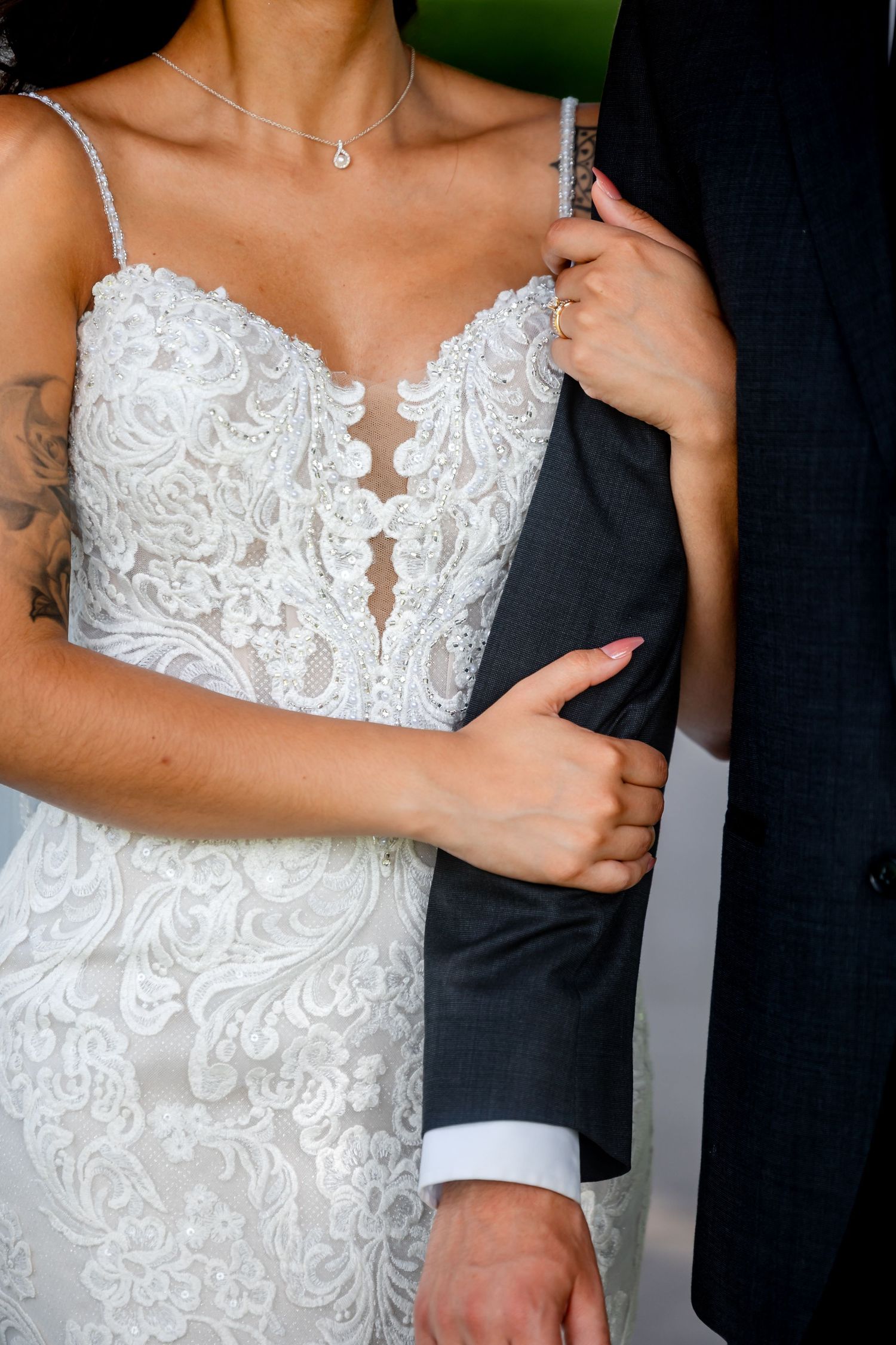 Close-up detail of an intricate white lace wedding dress with sweetheart neckline and delicate beading patterns.