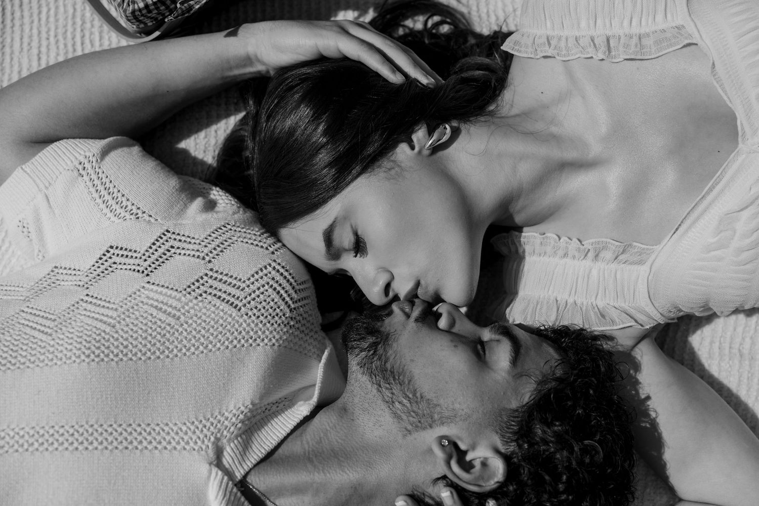 A romantic black and white photo of a couple lying close together.