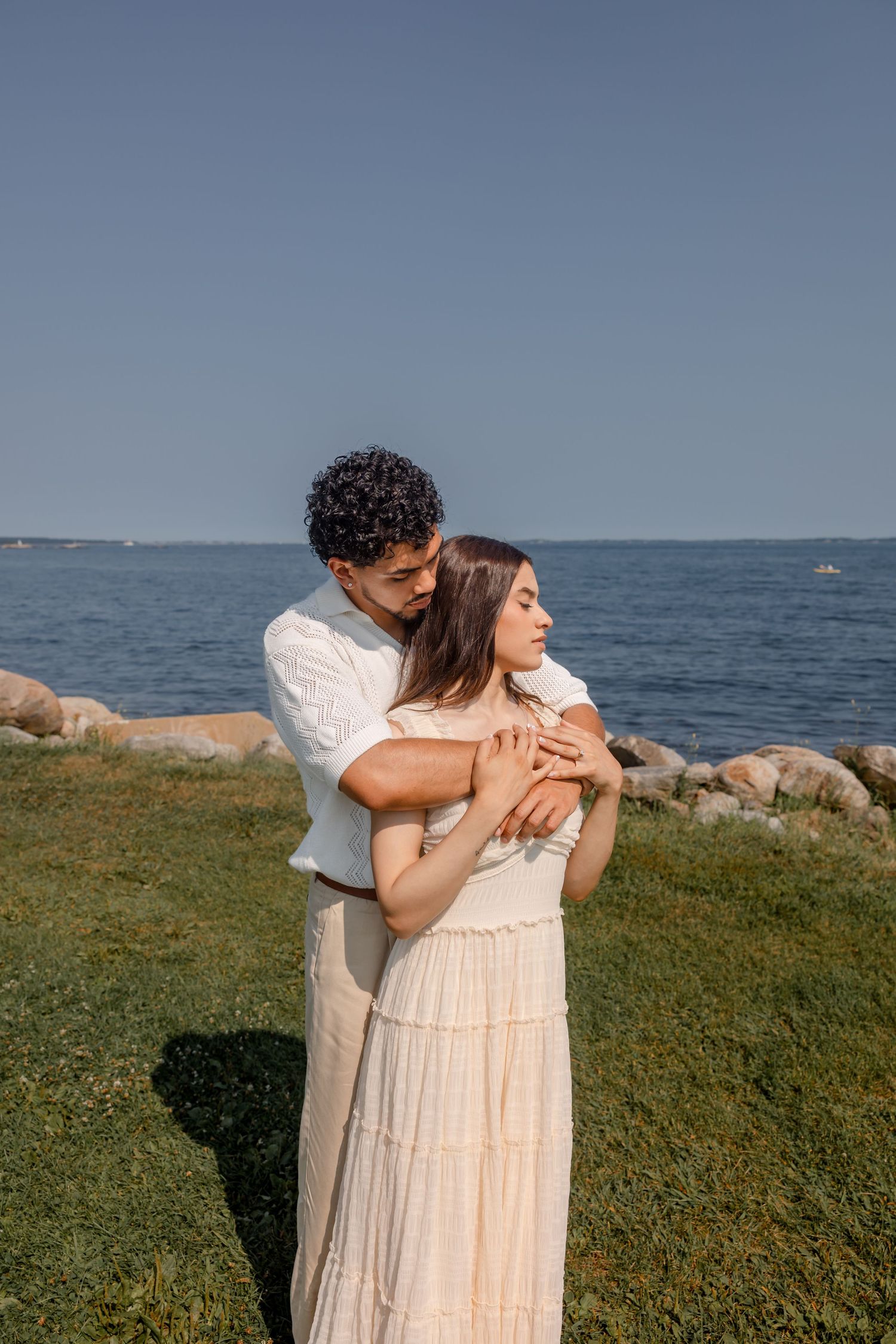 Couple in light colored clothing sharing an intimate moment by the seaside.