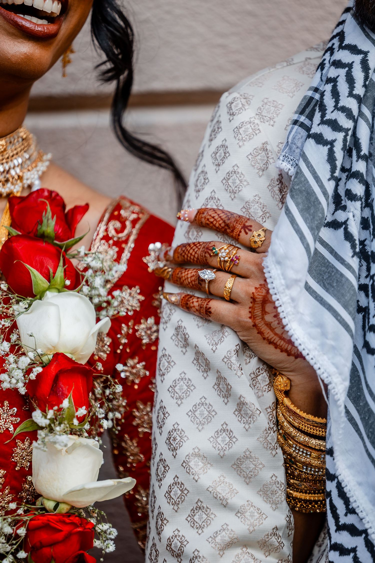 Detail shot of wedding jewelry, henna designs, and red and white roses in a traditional Indian ceremony.