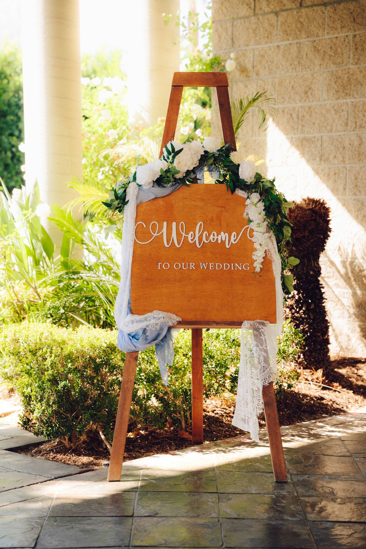 Wooden Welcome sign surrounded with flowers and greenery