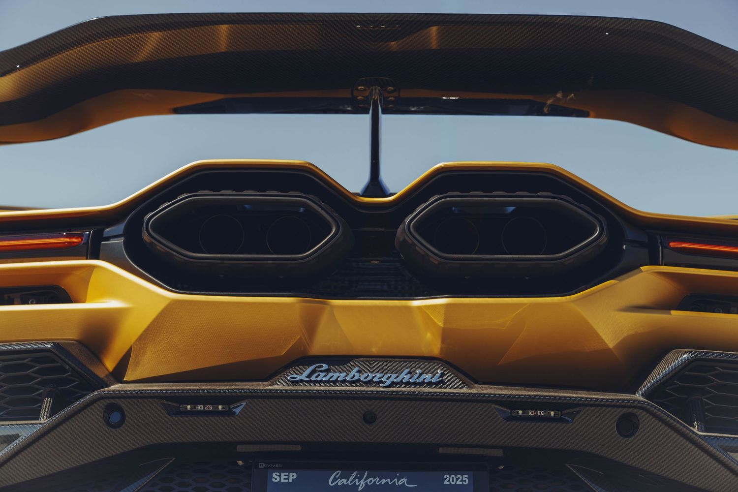 lamborghini revuelto in a yellow gold color rear shot of the exhaust tips with the wing on the top side