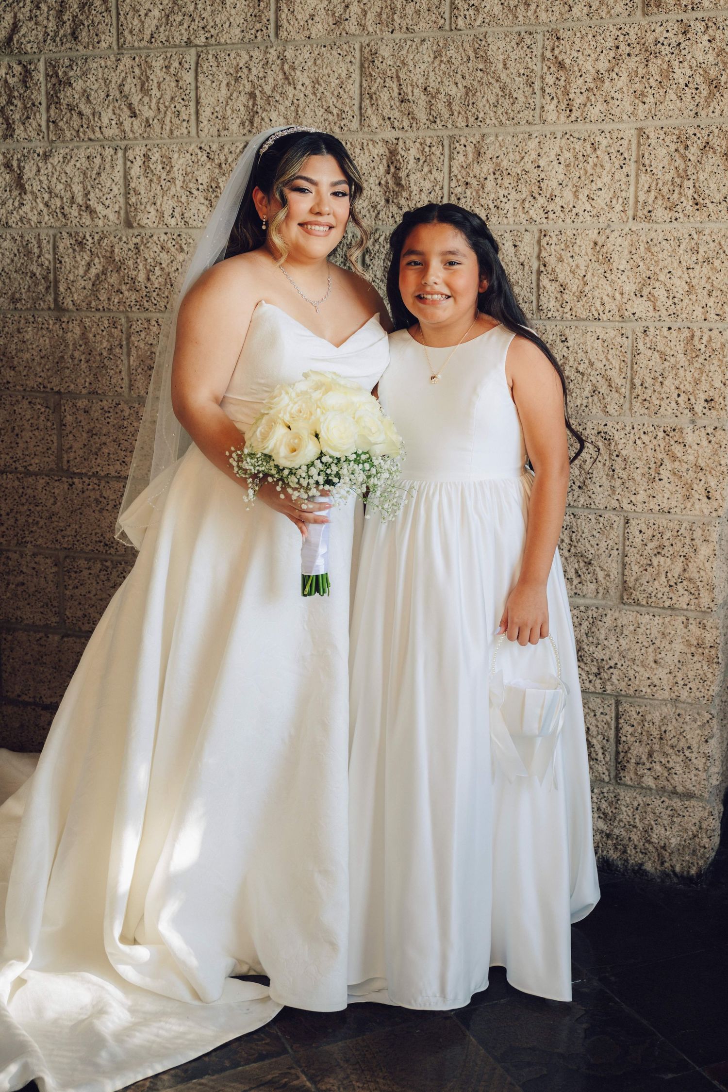 bride and daughter posing in front of a wall at the double tree hilton rosemead