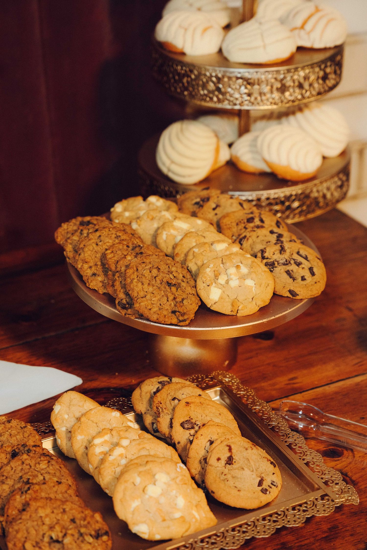 cookies layed out for wedding party on gold tiers