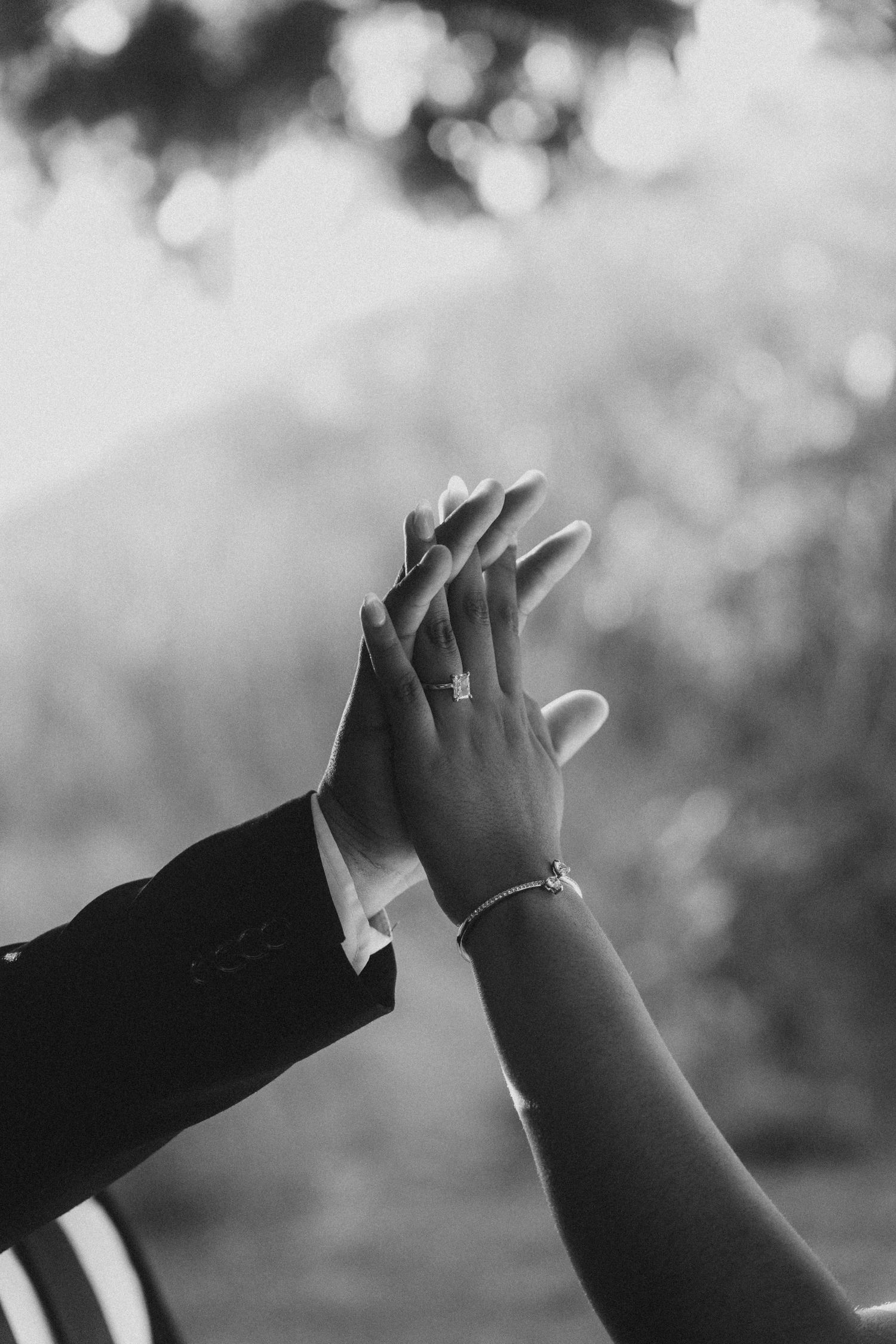 Close-up of couple’s hands with engagement ring at Red Wood Grove
