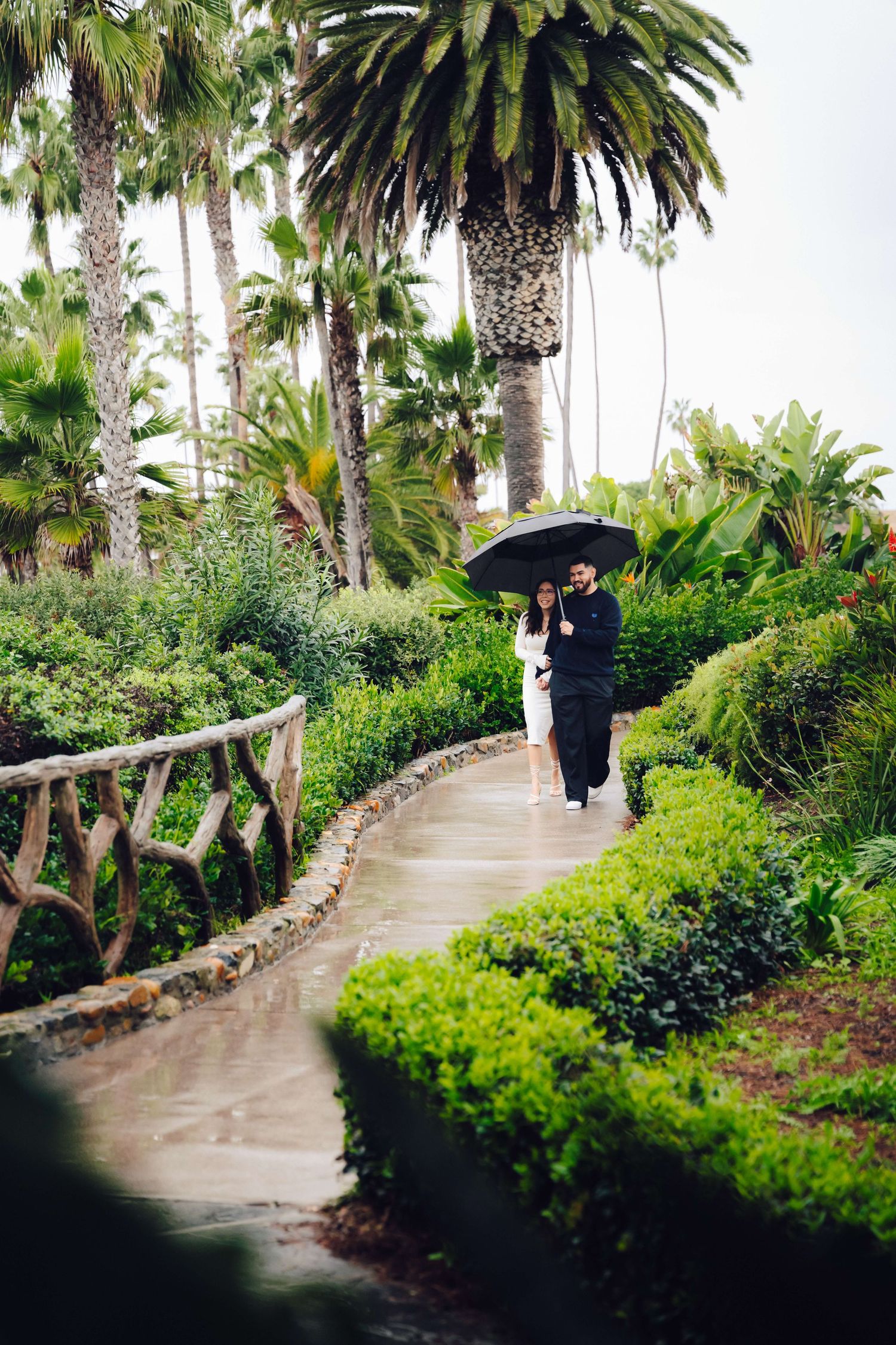 couple walking down a path surrounded with plants at laguna beach