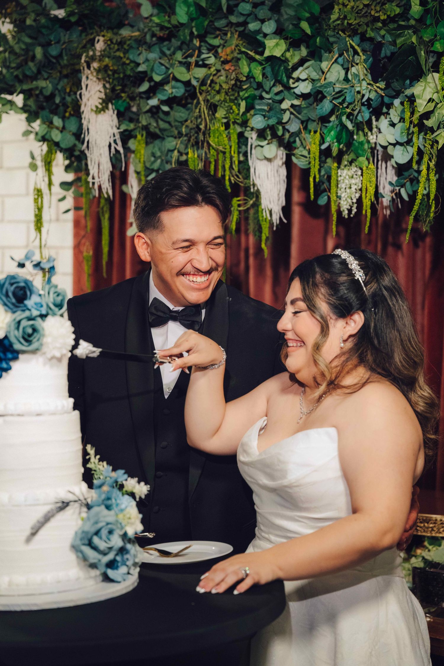 Groom and bride about to cut the cake while the groom is looking at her
