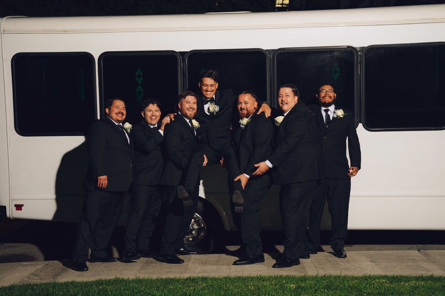 groomsmen picking up the groom in front of a party bus