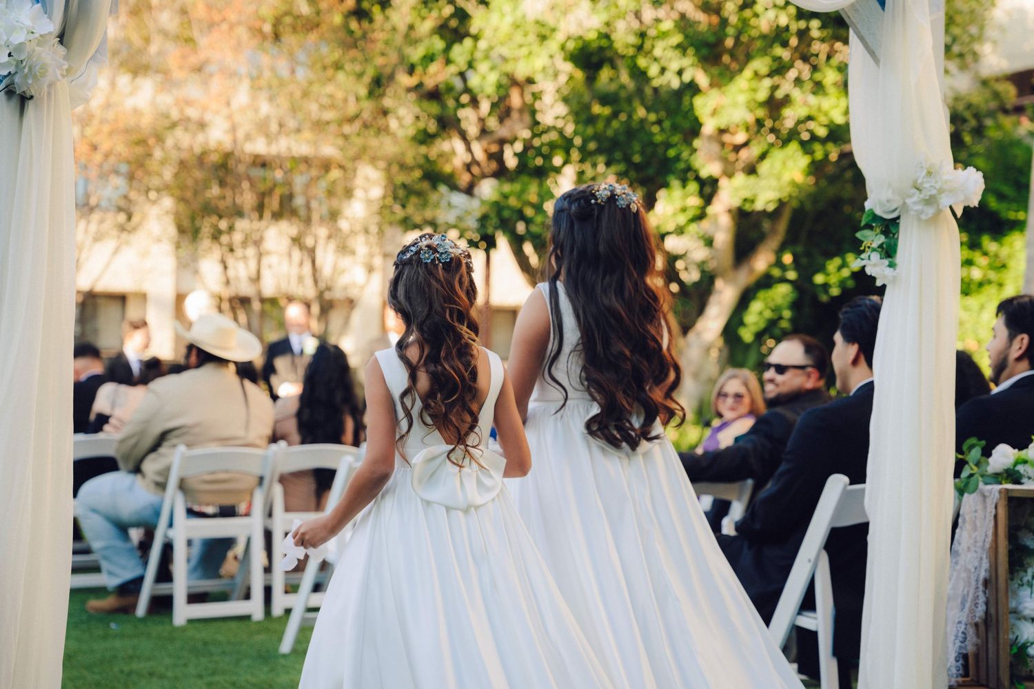 two flower girls walking down the aisle tossing flowers