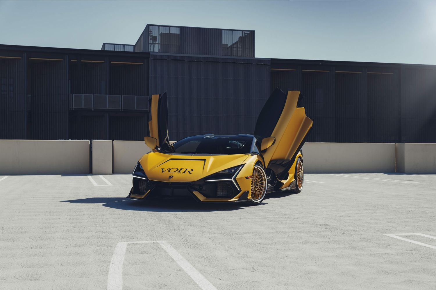 lamborghini revuelto in gold/ yellow with the doors up and wheel turned on a parking structure in tustin california