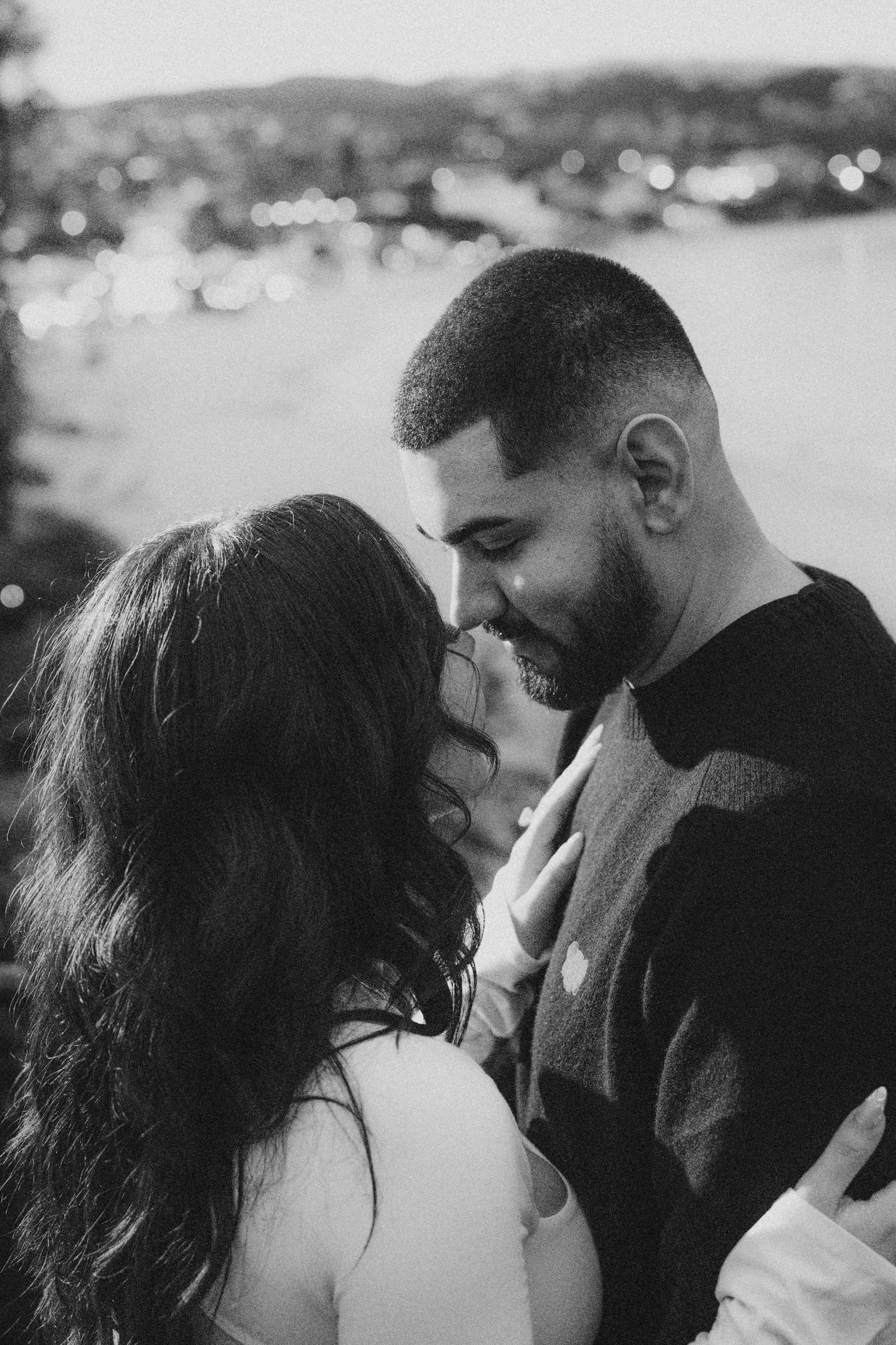 Black and white photo of a newly engaged couple while the skyline of Laguna Beach is in the background