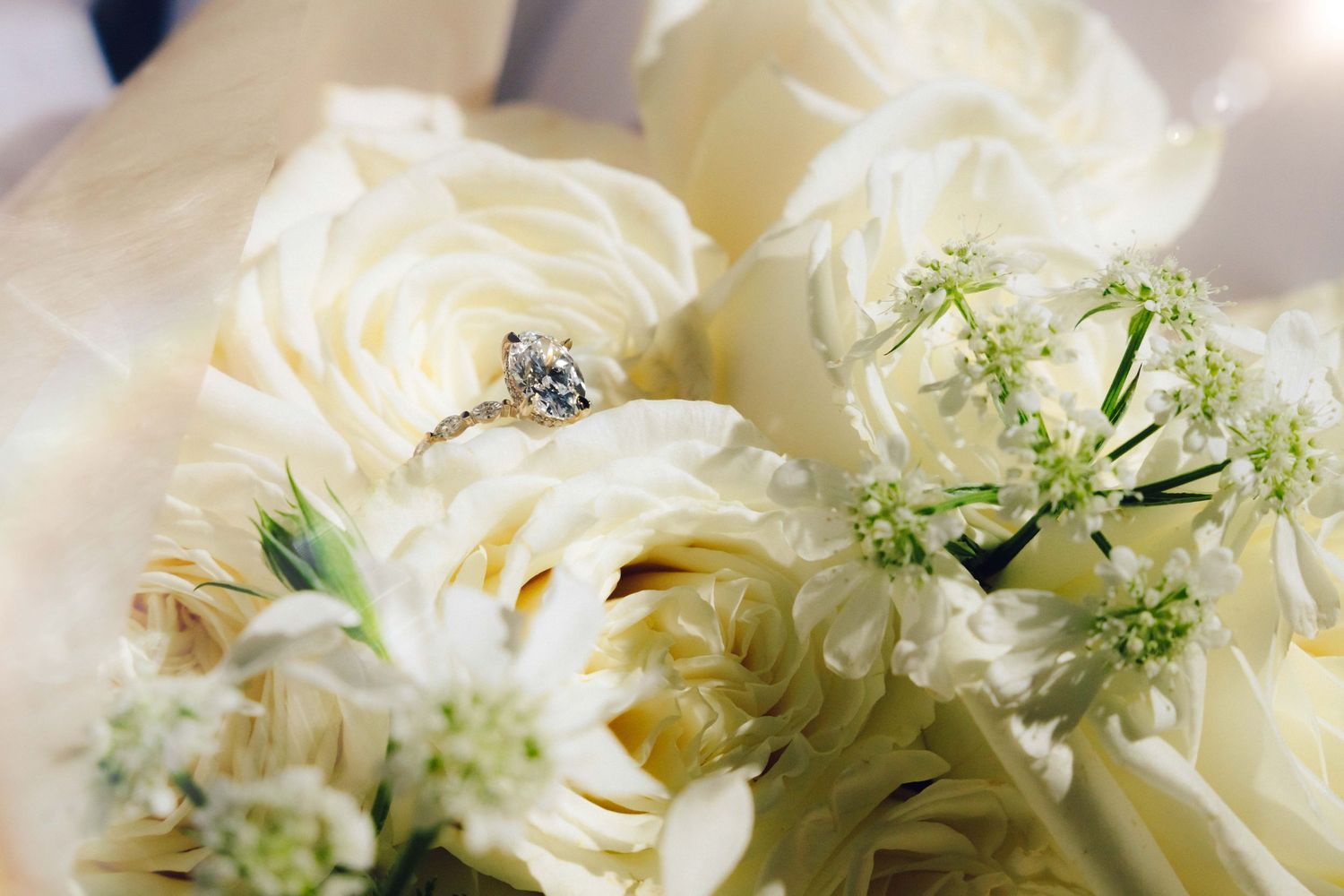 Wedding ring photo with the ring sitting on top of the white flowers