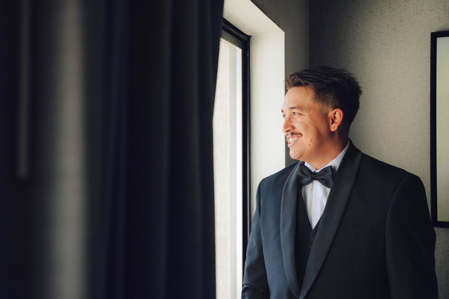 Groom smiling and starring outside with his wedding suit on
