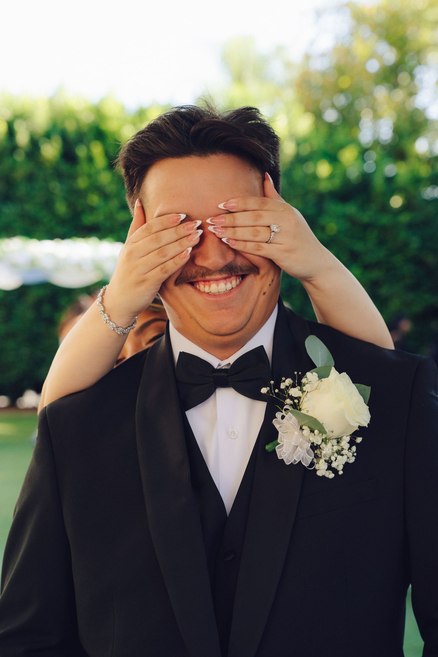 bride surprising groom by covering his eyes from behind