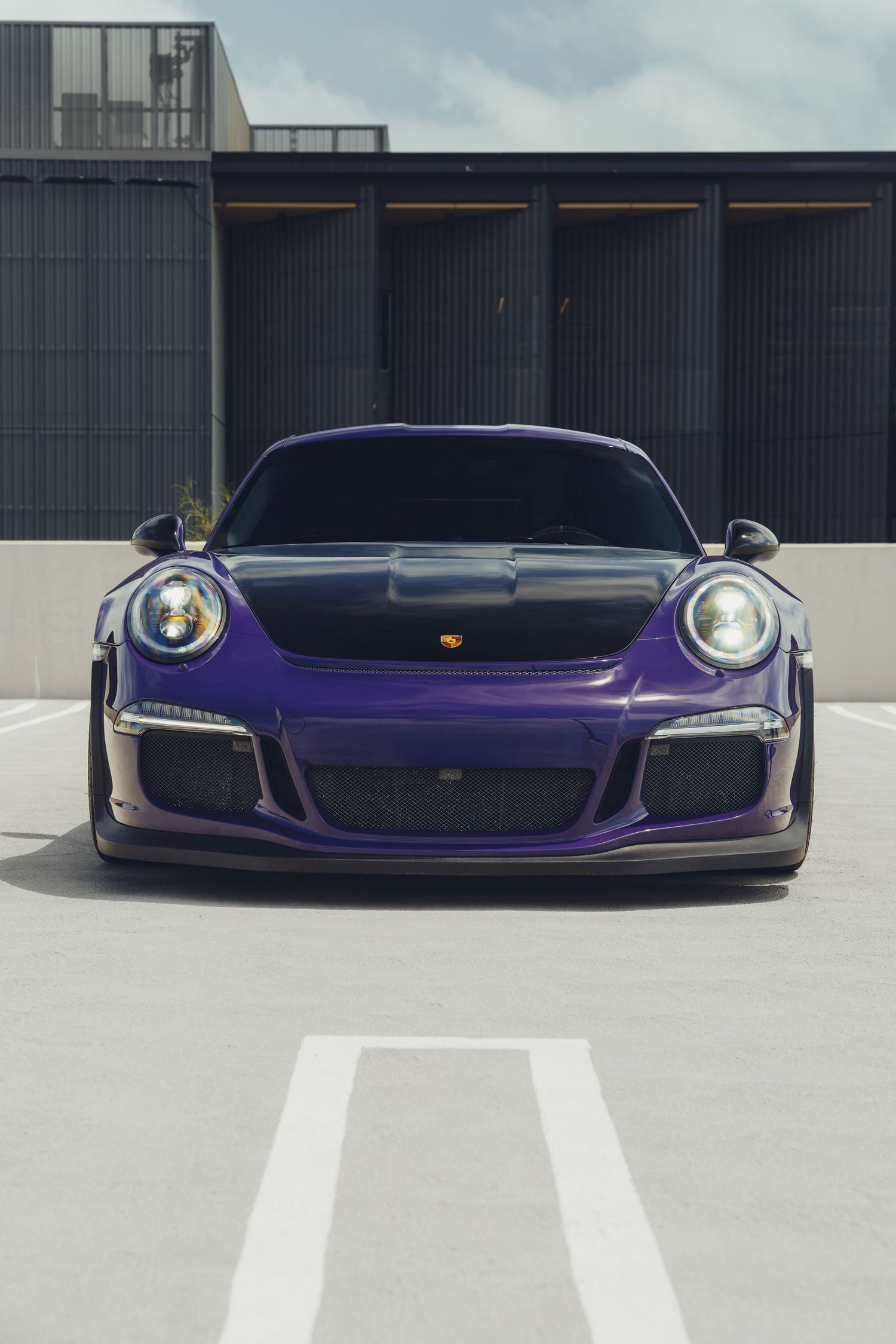 front profile of a porsche Gt3rs in a purple color with a black hood on a parking lot located in irvine california