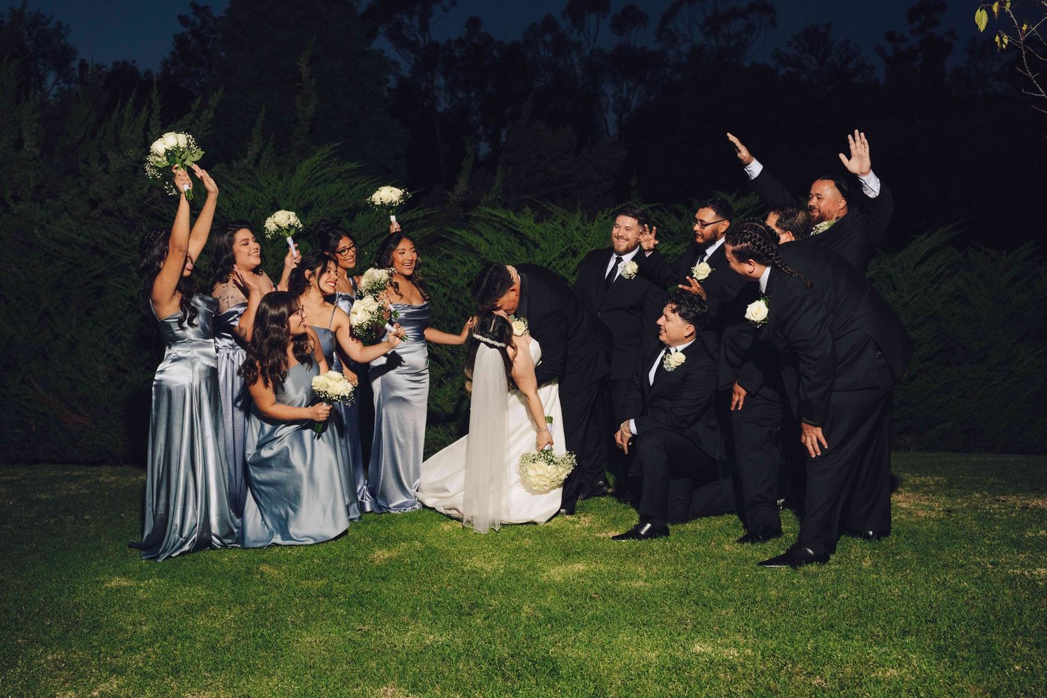 groom dipping his bride going for a kiss and the bridal party and groomsman shouting in excitement for them
