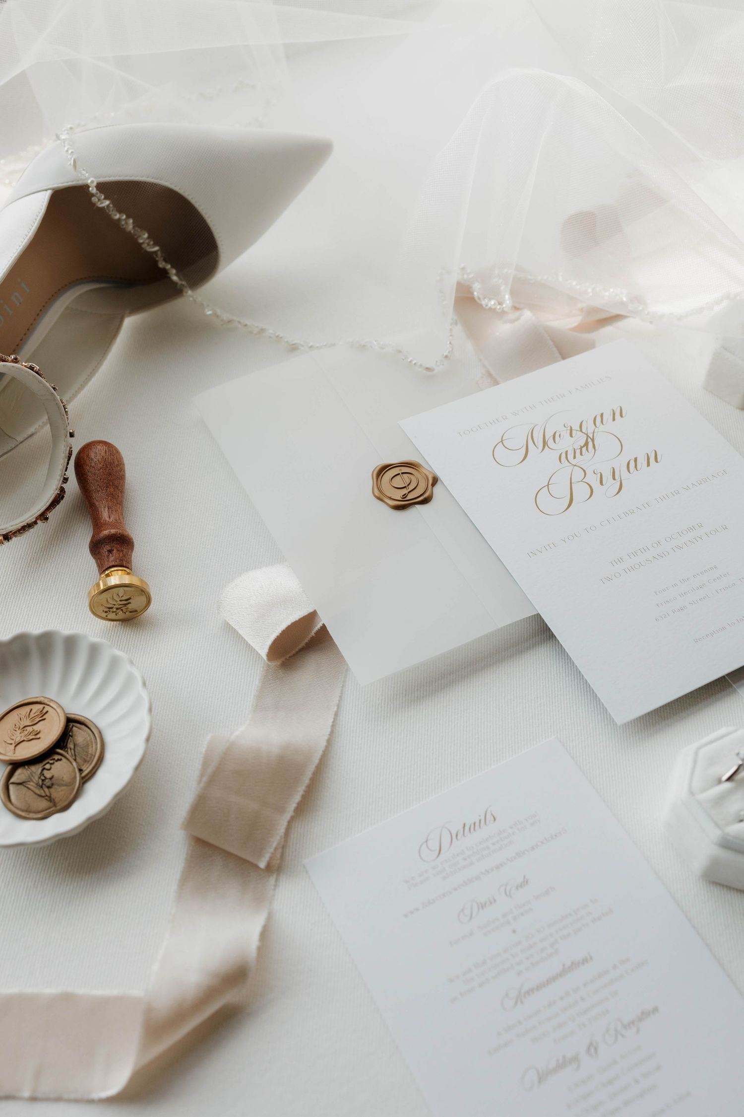 Elegant wedding invitation stationery with wax seals, silk ribbons and calligraphy on white surface with vintage stamps.
