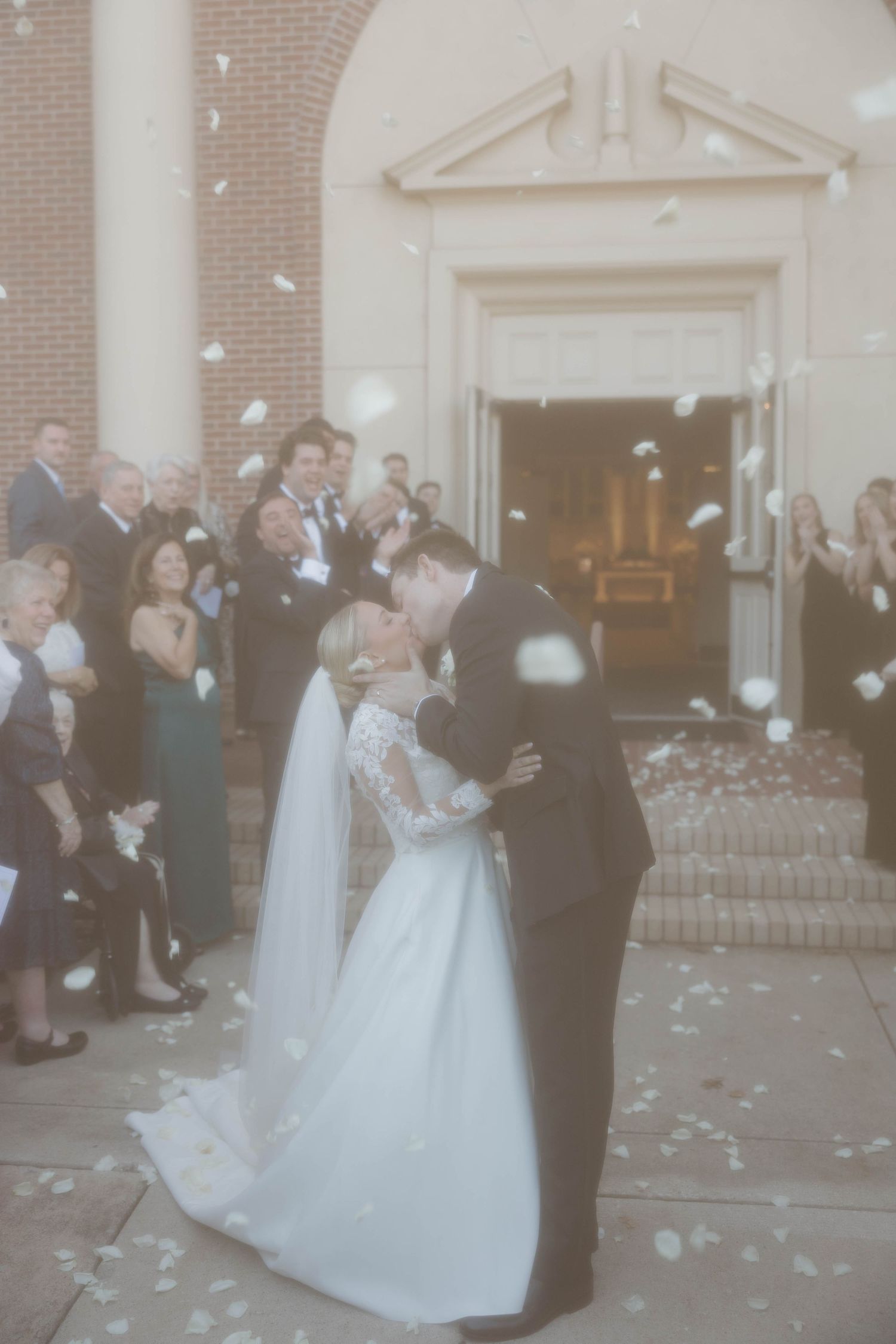 A couple dances together at their wedding celebration while guests blow bubbles around them on the church steps.