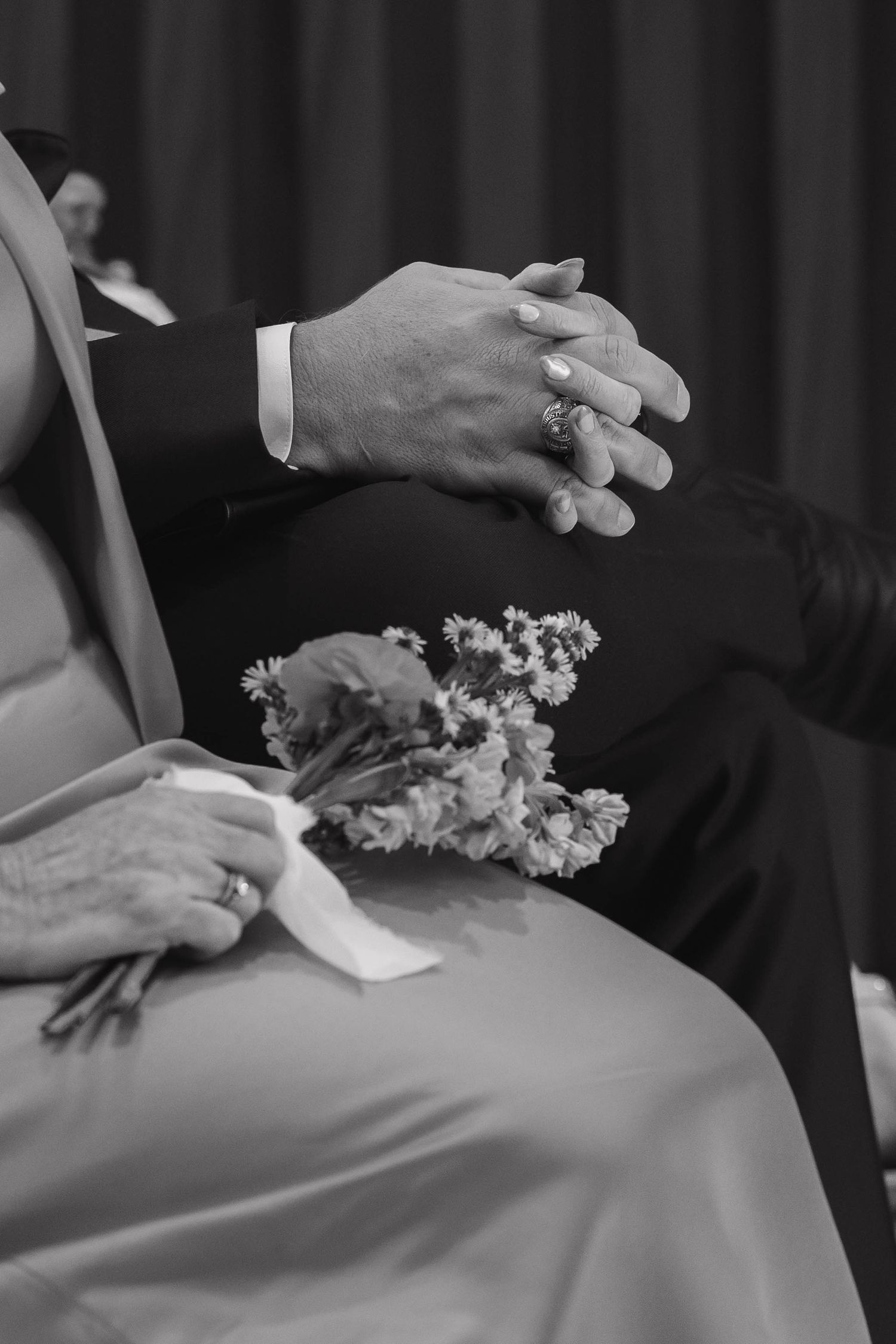 Black and white photo of hands and flowers at a formal event showing elegance and emotion.